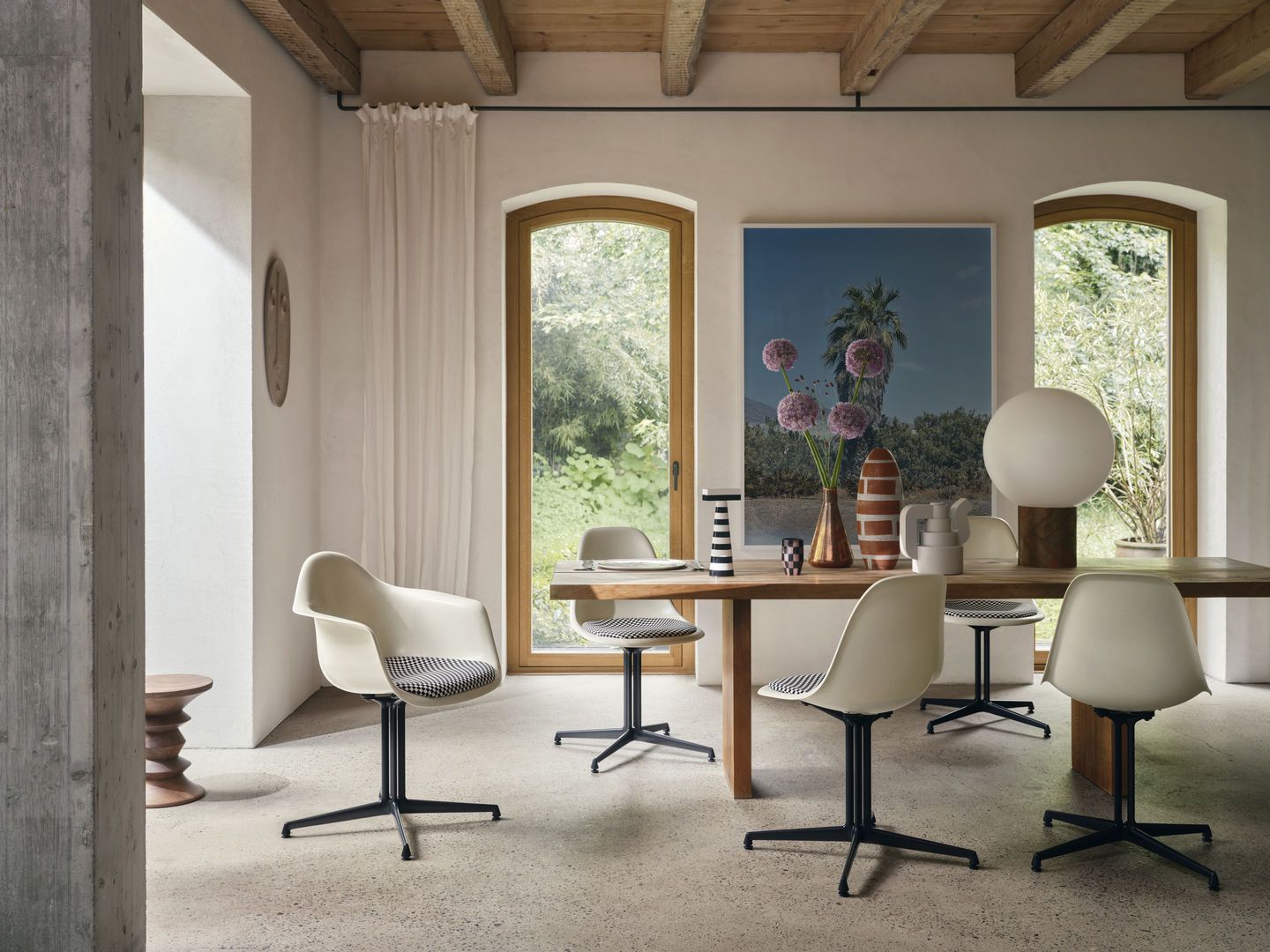Esszimmer mit Holztisch und mehreren weißen Eames Plastic Arm Chairs DAL mit Sitzpolster von Vitra.