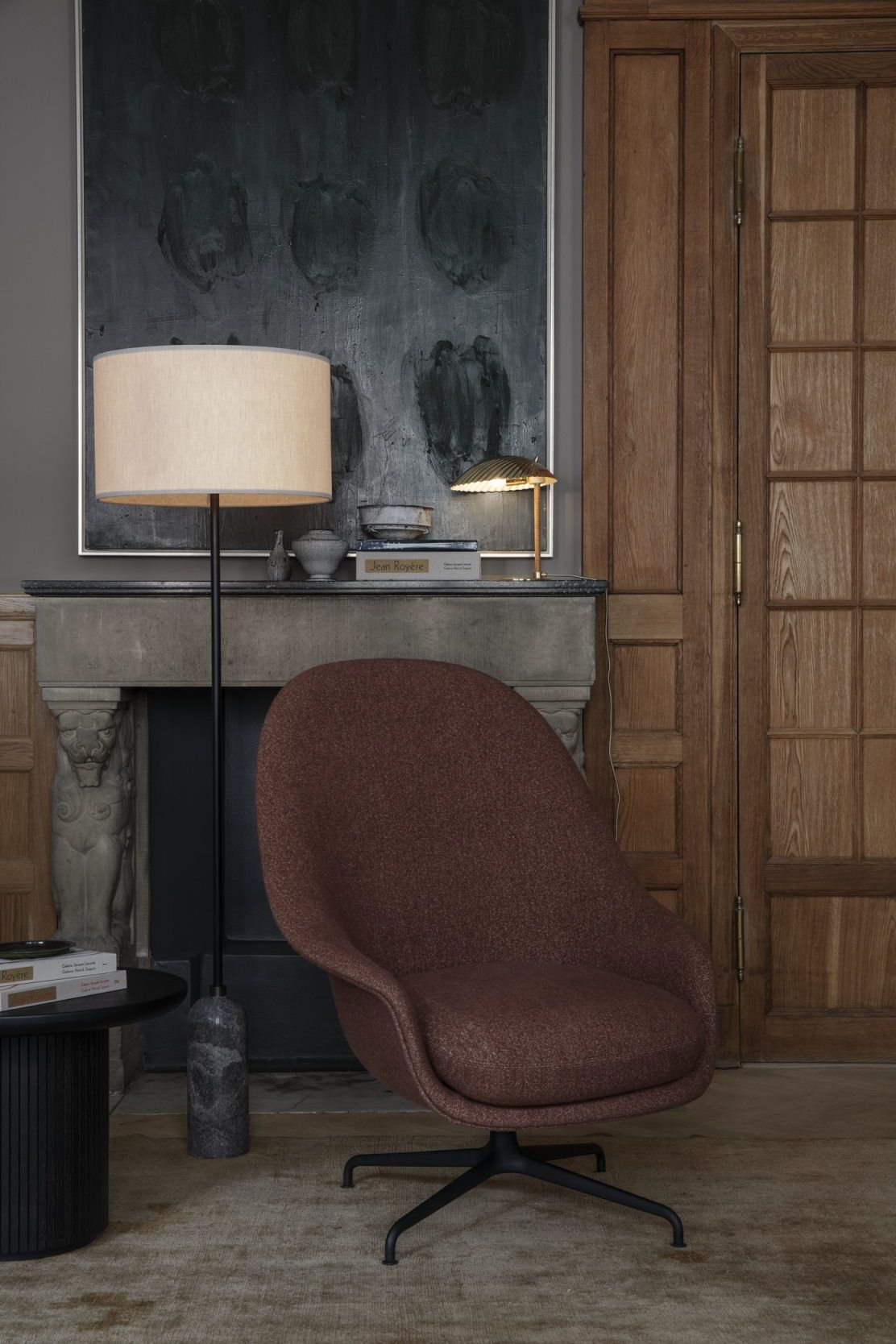 Brauner Sessel neben einem schwarzen Gubi Couchtisch und Stehlampe in einem Wohnzimmer.