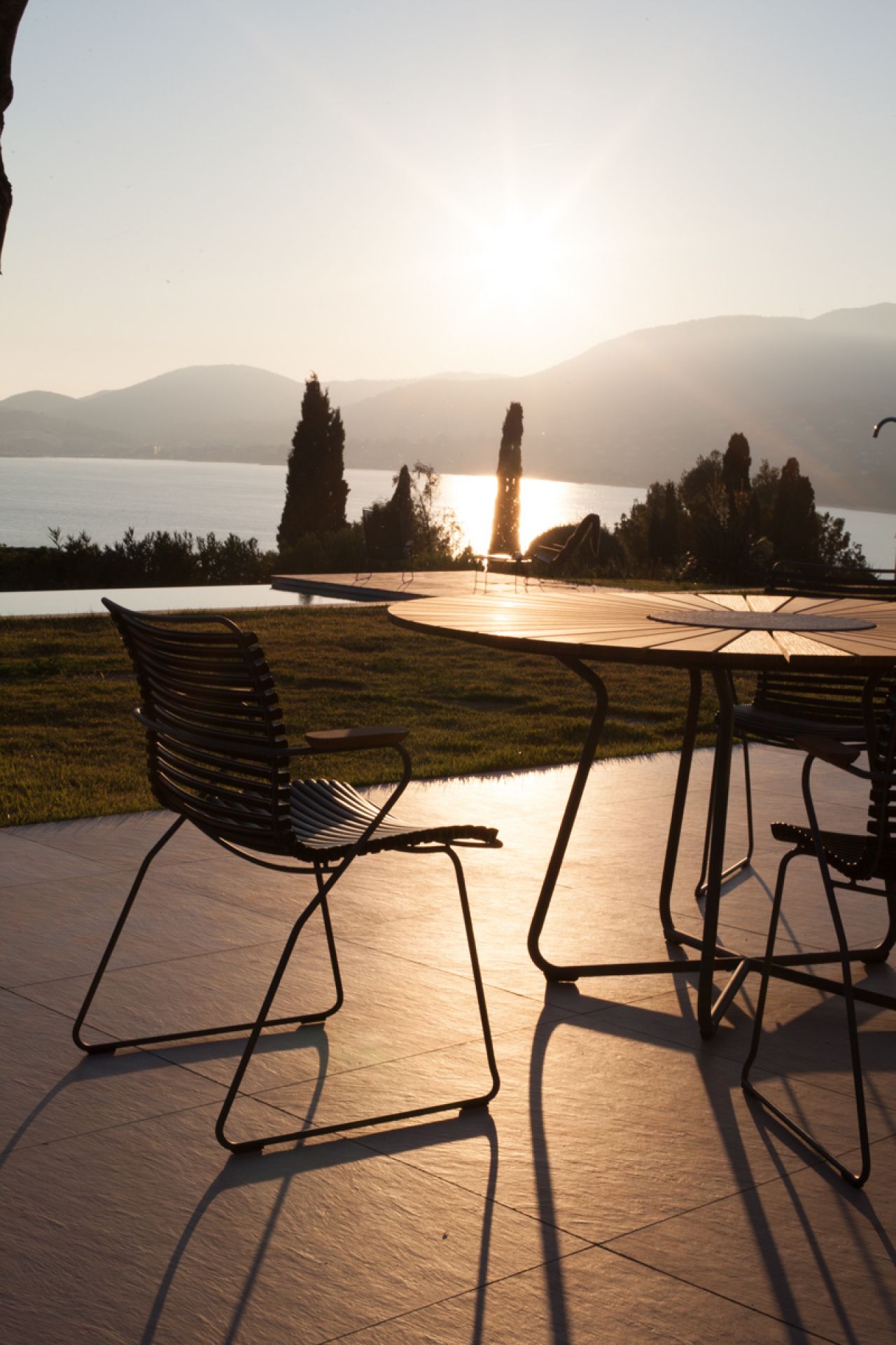 Houe Circle Outdoor Tisch 150 cm aus Bambus mit Stühlen bei Sonnenuntergang im Garten.
