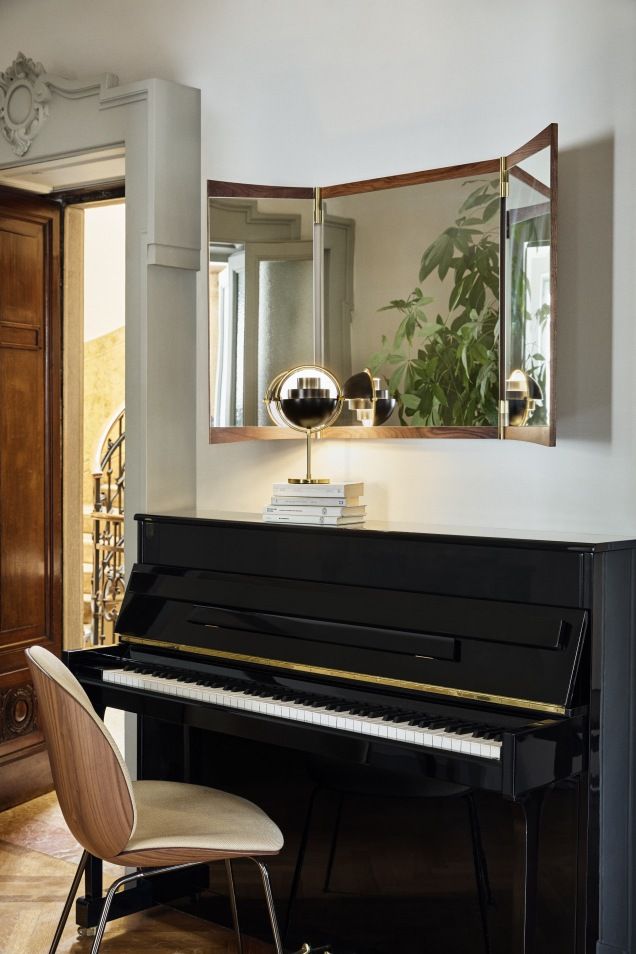 Gubi Vanity Wall Mirror 3 Wandspiegel über schwarzem Klavier mit Lampe und Stuhl im eleganten Interieur.