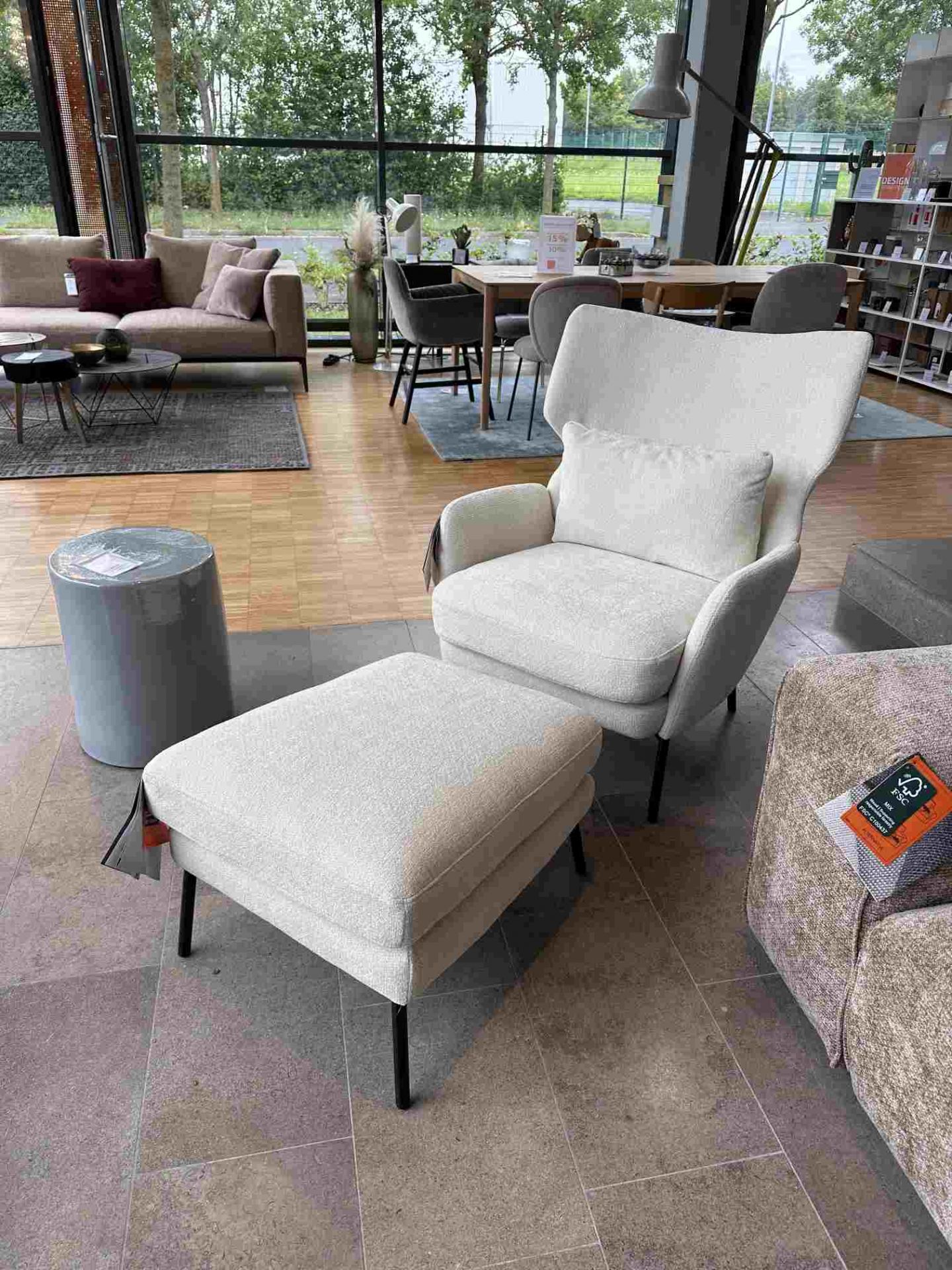 Seatrelax Sessel mit Ottoman im modernen Design, hellgrauer Stoffbezug und schlanke, schwarze Füße.