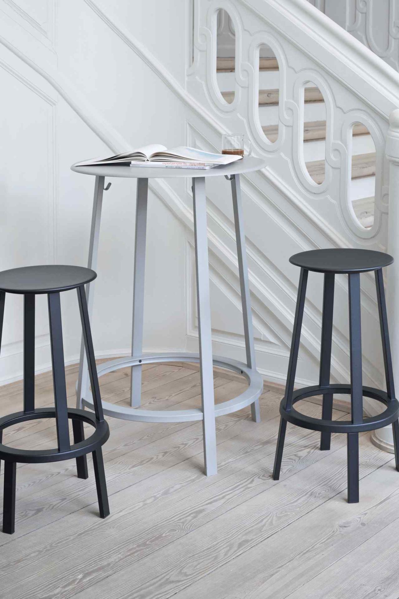 Zwei graue Barhocker und ein Stehtisch von Hay, Modell Revolver Bar Stool High, im Treppenhaus.