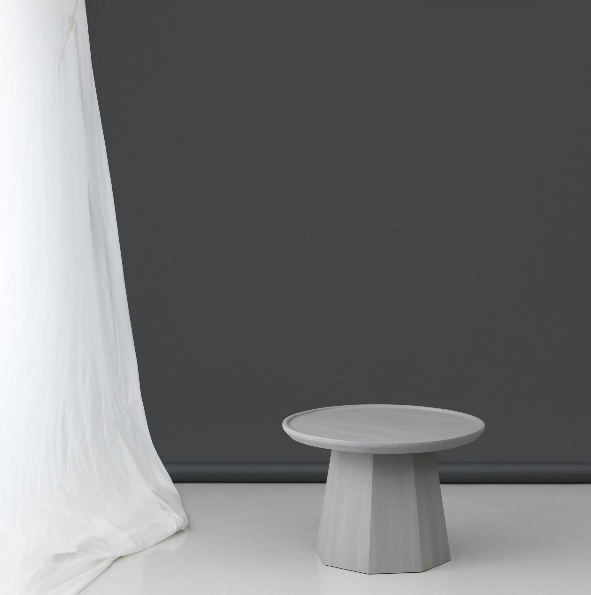 Grauer Pine Table Large Beistelltisch von Normann Copenhagen vor dunklem Hintergrund und weißem Vorhang.