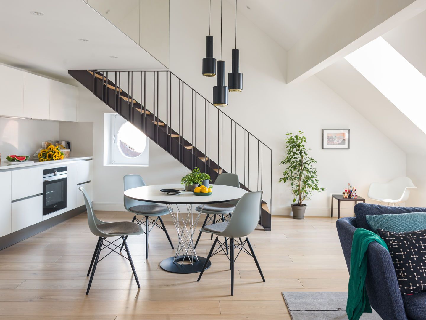 Helle Wohnungseinrichtung mit Esstisch und vier grauen Eames Plastic Side Chairs DSW von Vitra.