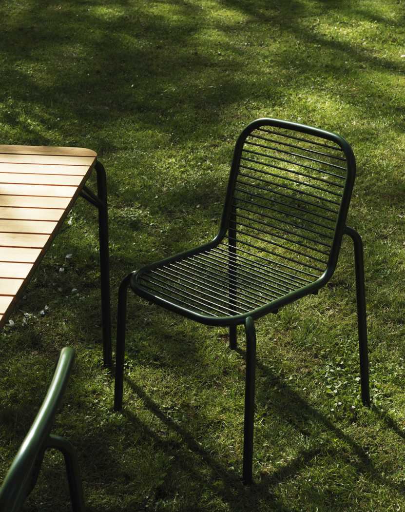 Normann Copenhagen Vig Chair Outdoor Stuhl in Dunkelgrün auf Rasen mit Gartentisch.