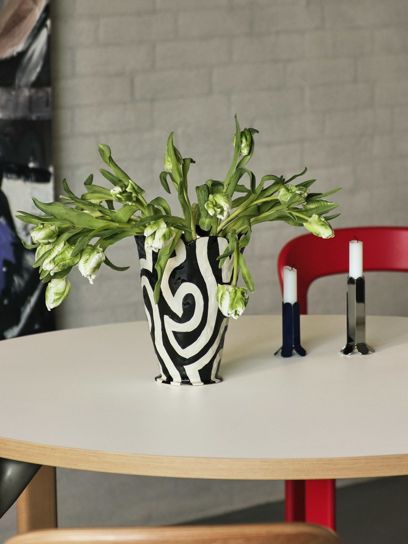 Nahaufnahme von Hay Arcs Kerzenständern und einer Vase mit Blumen auf einem runden Tisch.