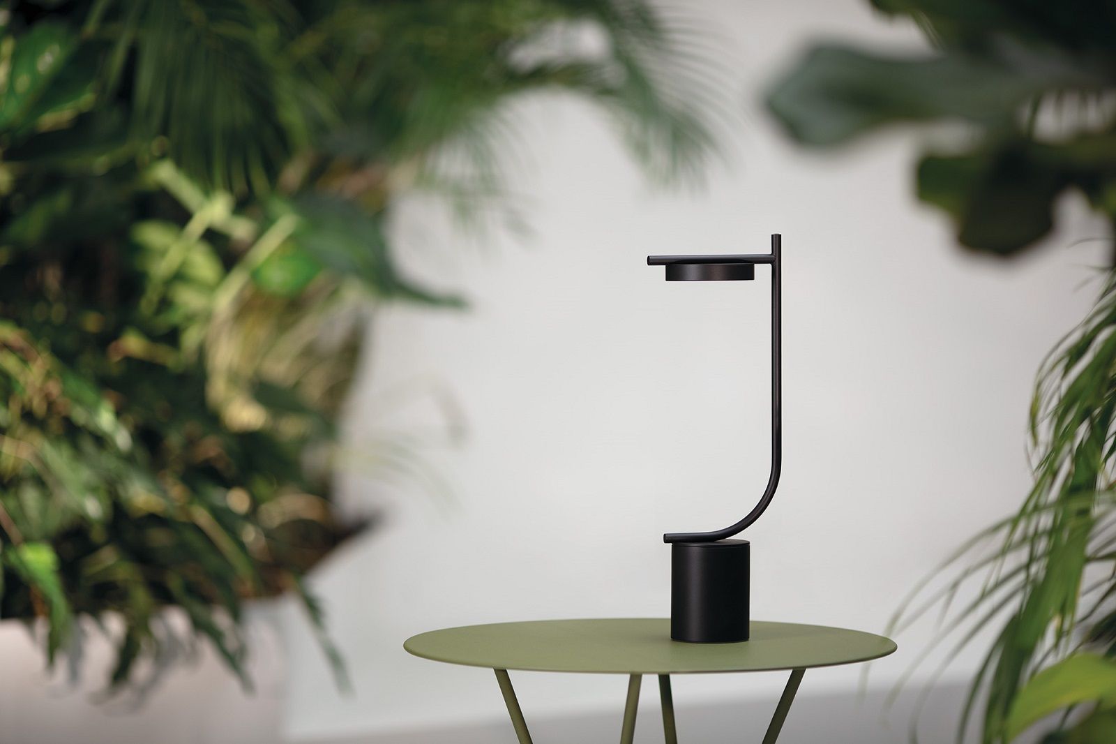 Schwarze Igram Akku Tischleuchte von Grupa auf grünem Tisch, minimalistisches Design für Wohnraum und Büro.
