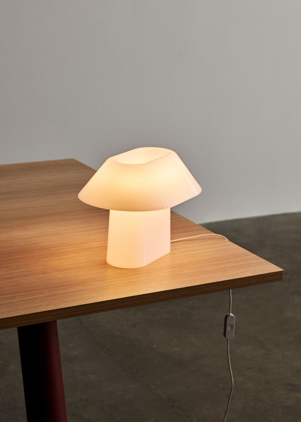 Nahaufnahme der Drome Tischleuchte von Hay auf einem Holztisch, warmes Licht.