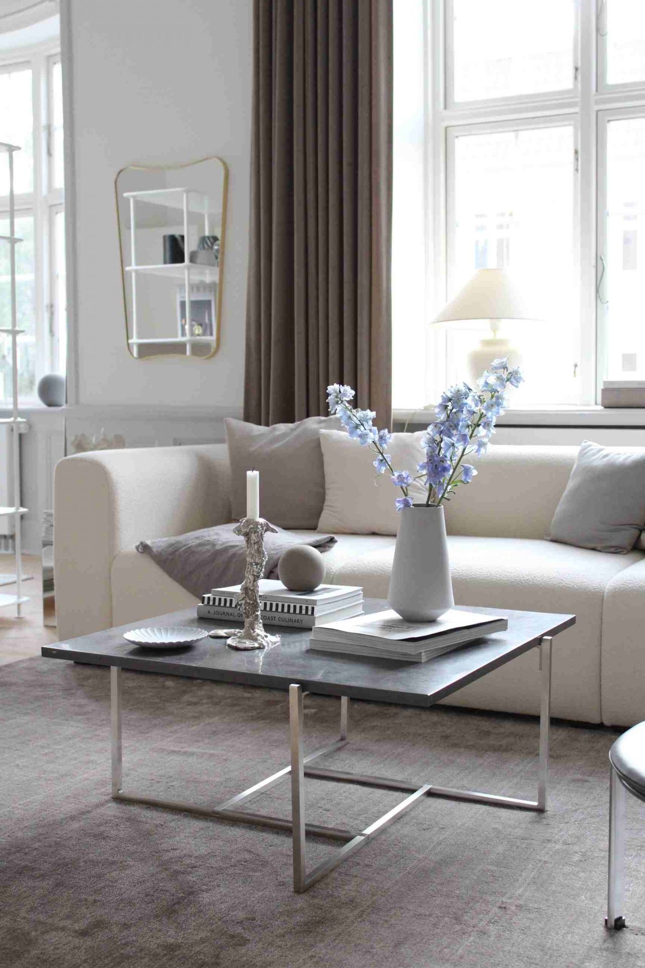 Wohnzimmer-Szene mit grauem Tint Rug Teppich von Woud, Couch, Tisch und Dekoration für gemütliches Ambiente.