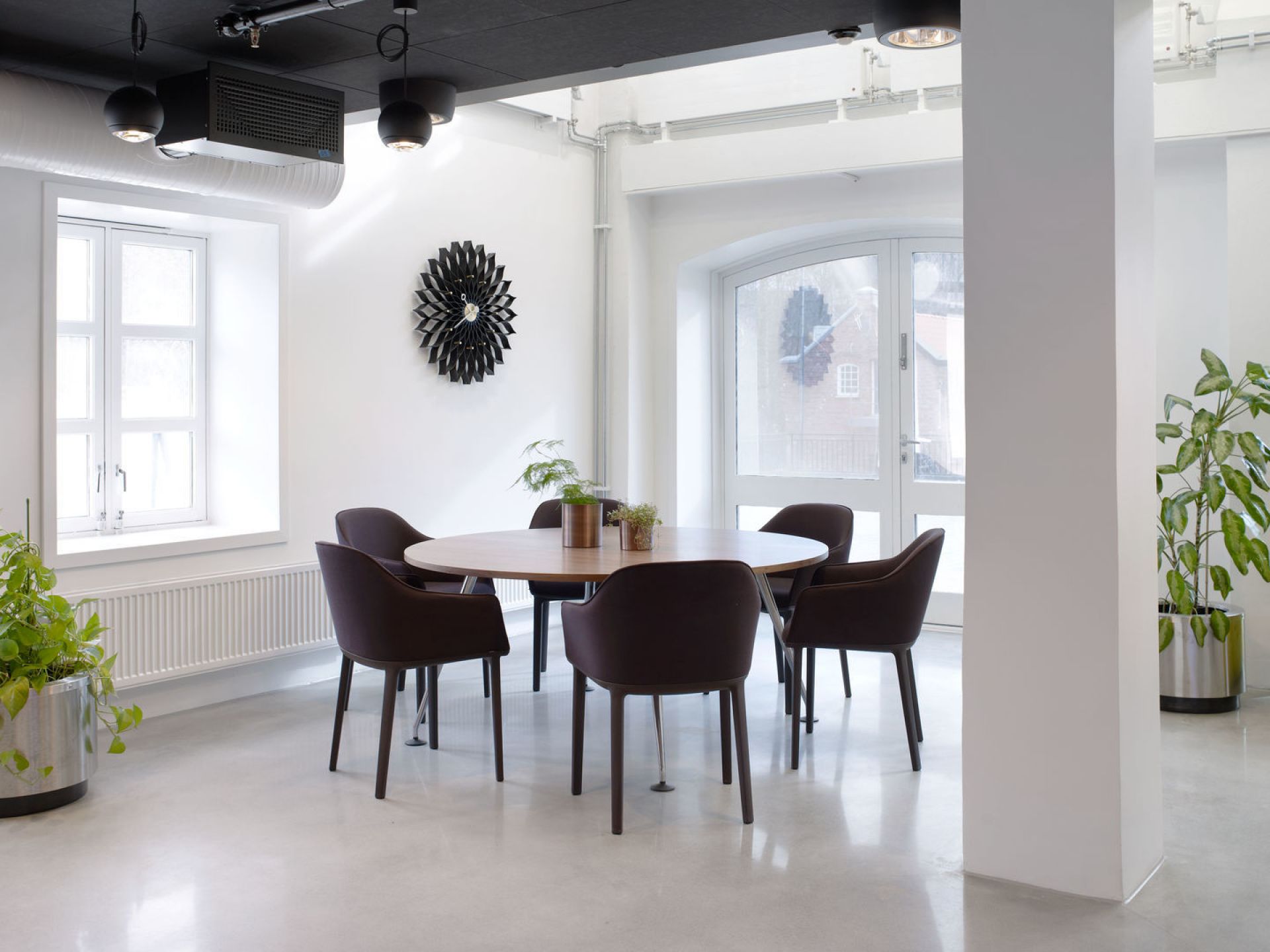 Vitra Softshell Chair mit Vierfußgestell in Braun um einen runden Holztisch in hellem Raum.