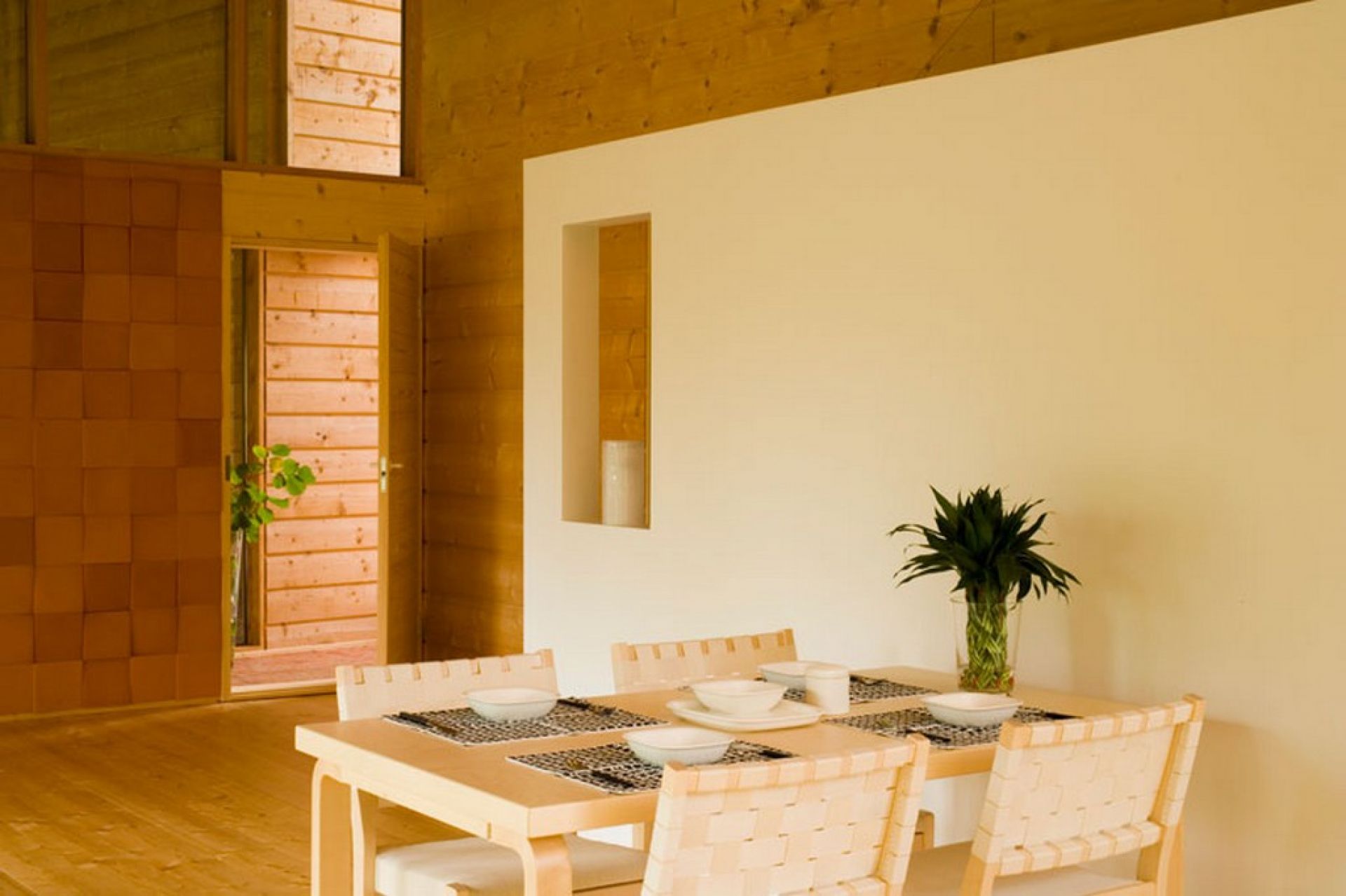 Helle Holzstühle vom Typ Artek 611 um einen Esstisch in einem modernen, minimalistischen Esszimmer.