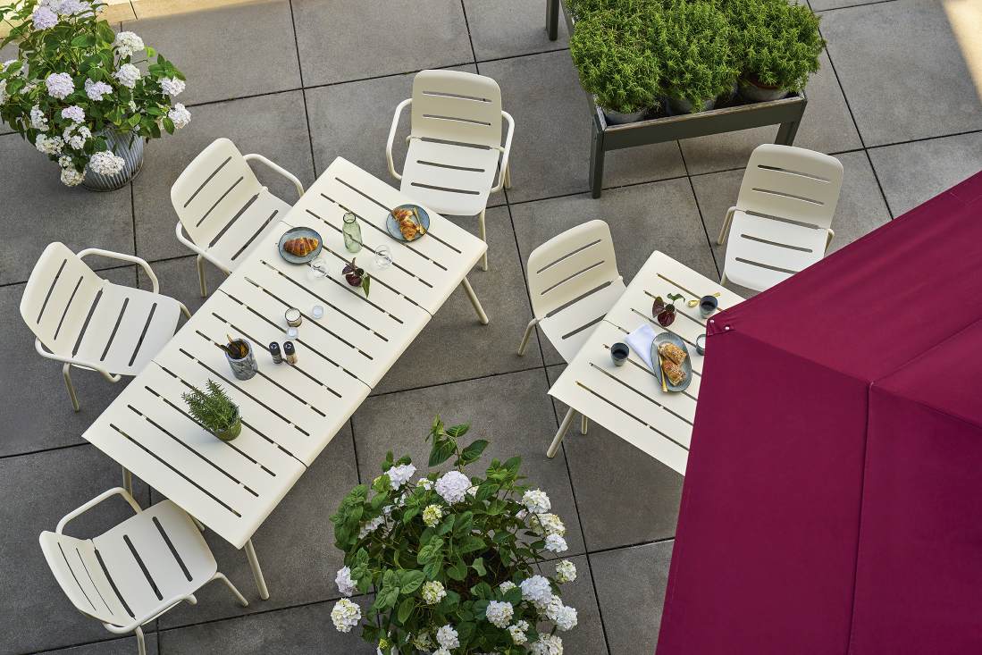 Vapio Tisch Outdoor von Weishäupl mit Stühlen auf einer Terrasse, gedeckt mit Speisen und Getränken.