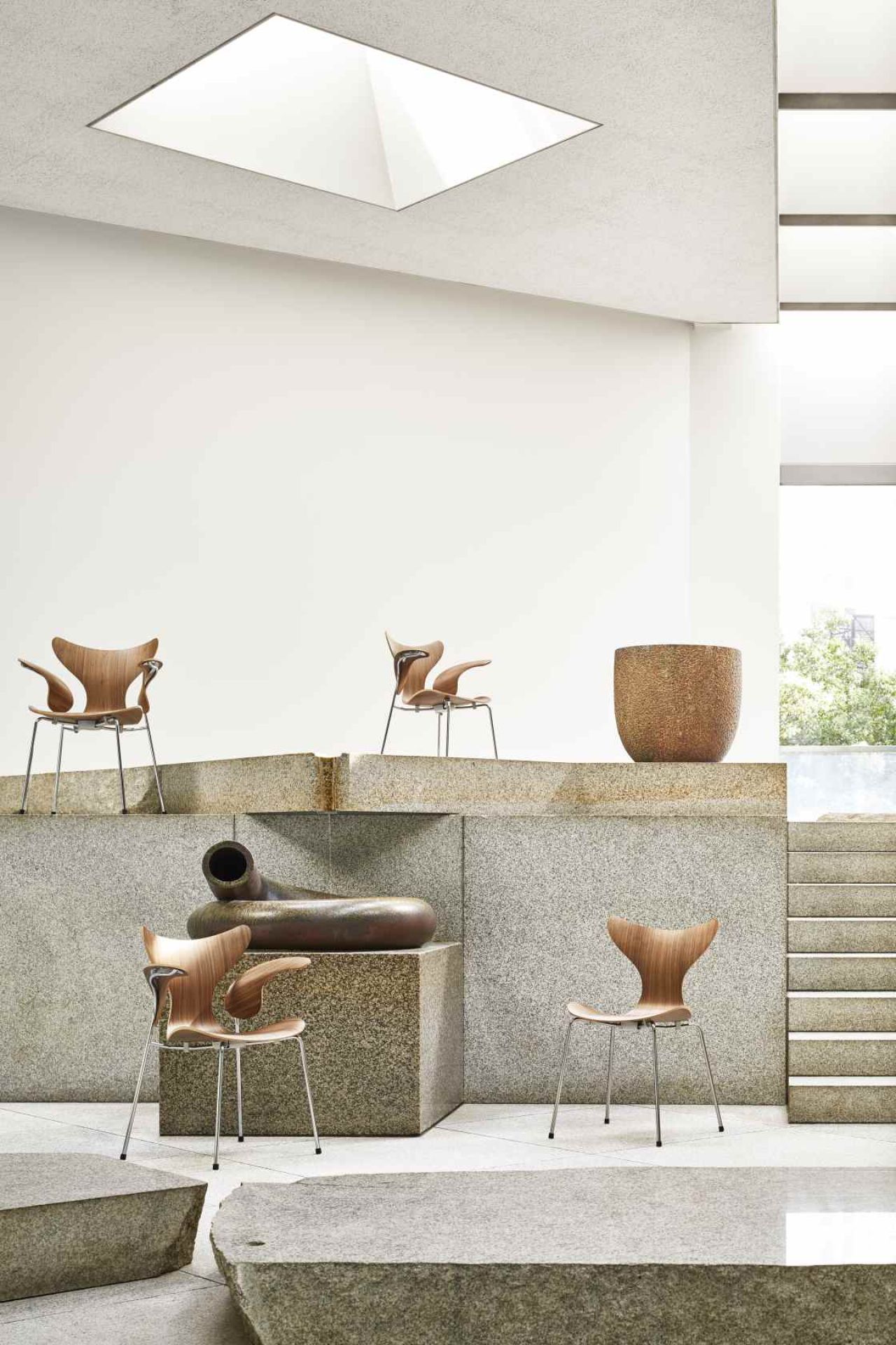Fritz Hansen Lily Armlehnstuhl 3208 aus Holz und Stahl in modernem Ausstellungsraum.