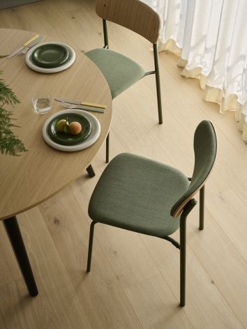 Thonet S 243 PV Stahlrohrstuhl mit grüner Polsterung an Sitzfläche und Rückenlehne am Esstisch.