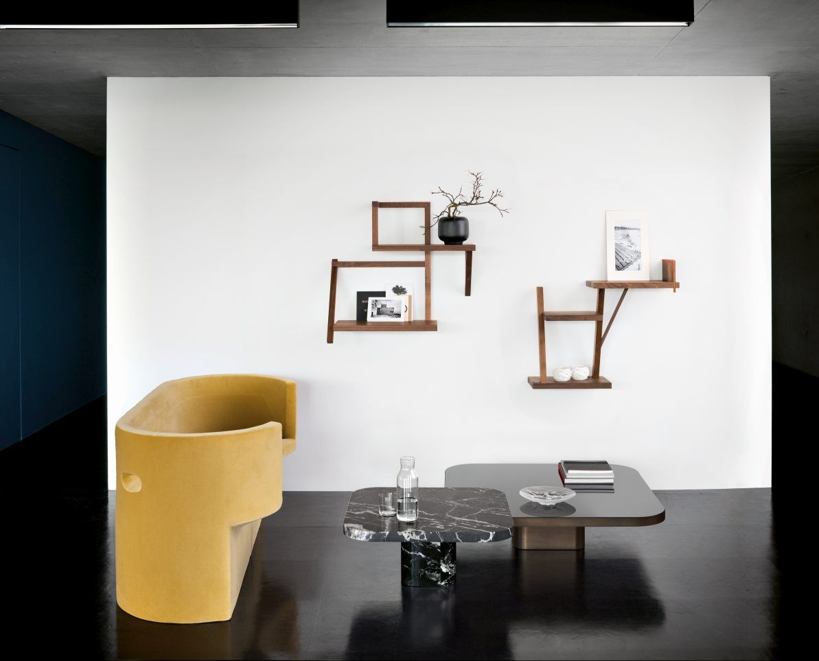 ClassiCon Bow Coffee Table No.1 Couchtisch im modernen Wohnzimmer mit gelbem Sessel und Wandregalen.