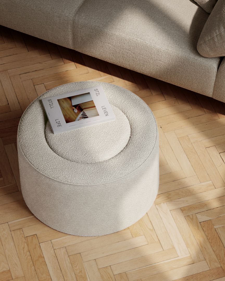 Beiger Praline Hocker von Woud, runder Pouf mit Magazin auf hellem Holzboden.