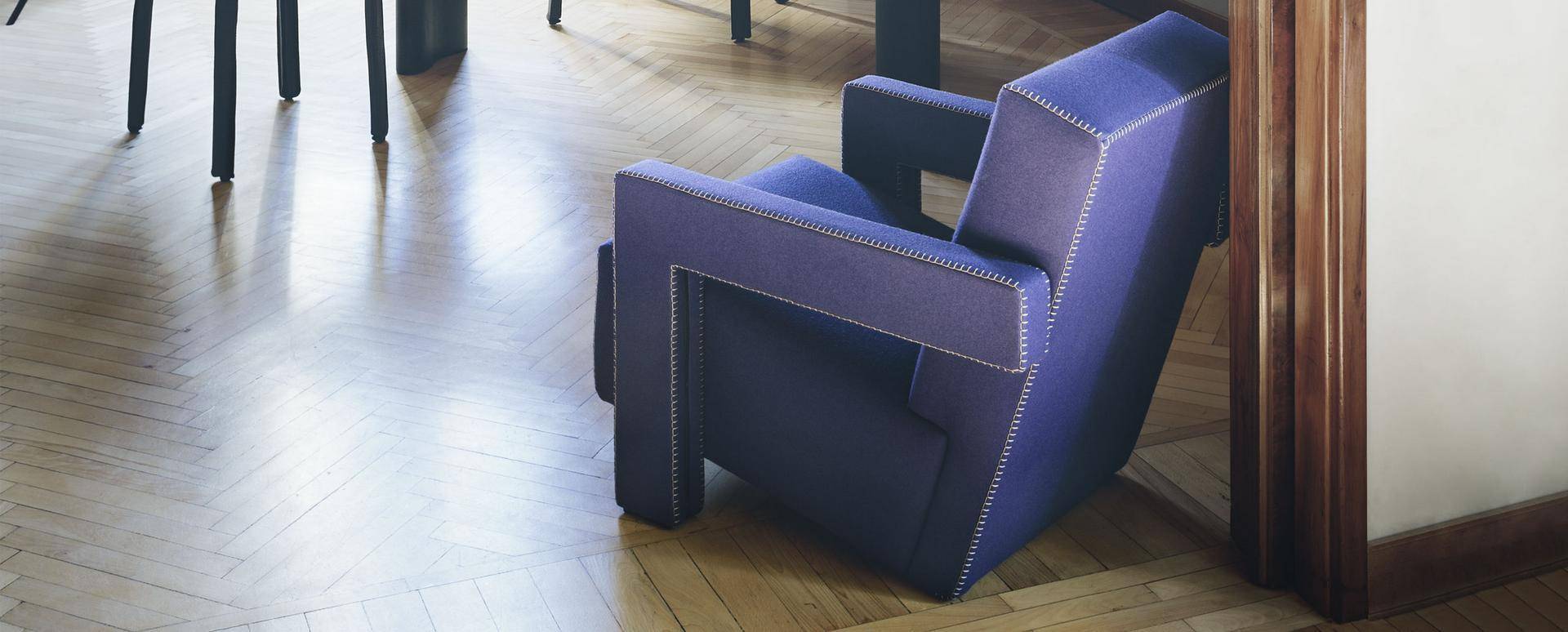 Nahaufnahme des Cassina Utrecht Sessels in Lila mit markanten Ziernähten auf Parkettboden.