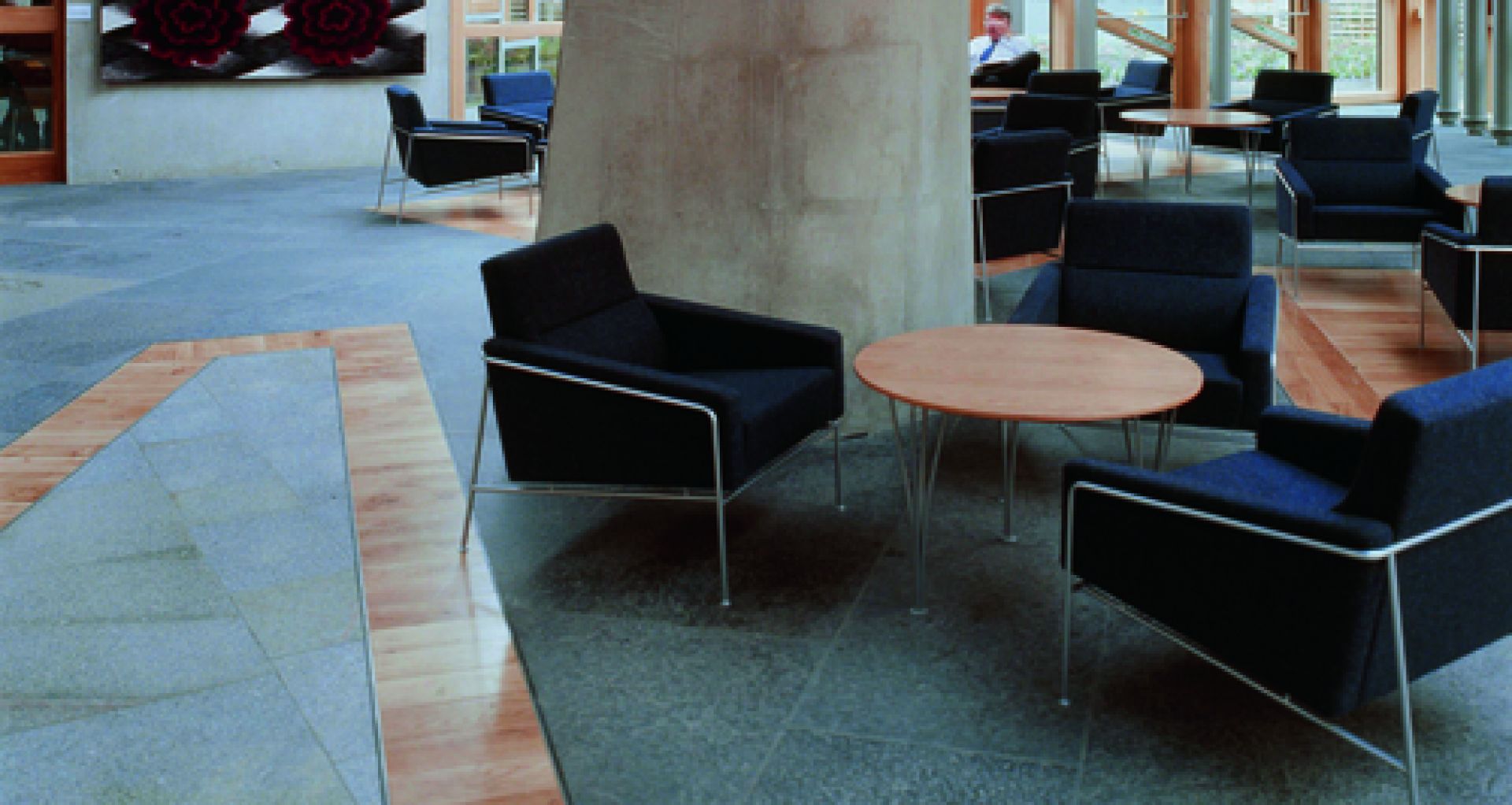 Innenaufnahme mit mehreren Fritz Hansen Serie 3300 Sofas in Schwarz und Holztischen.