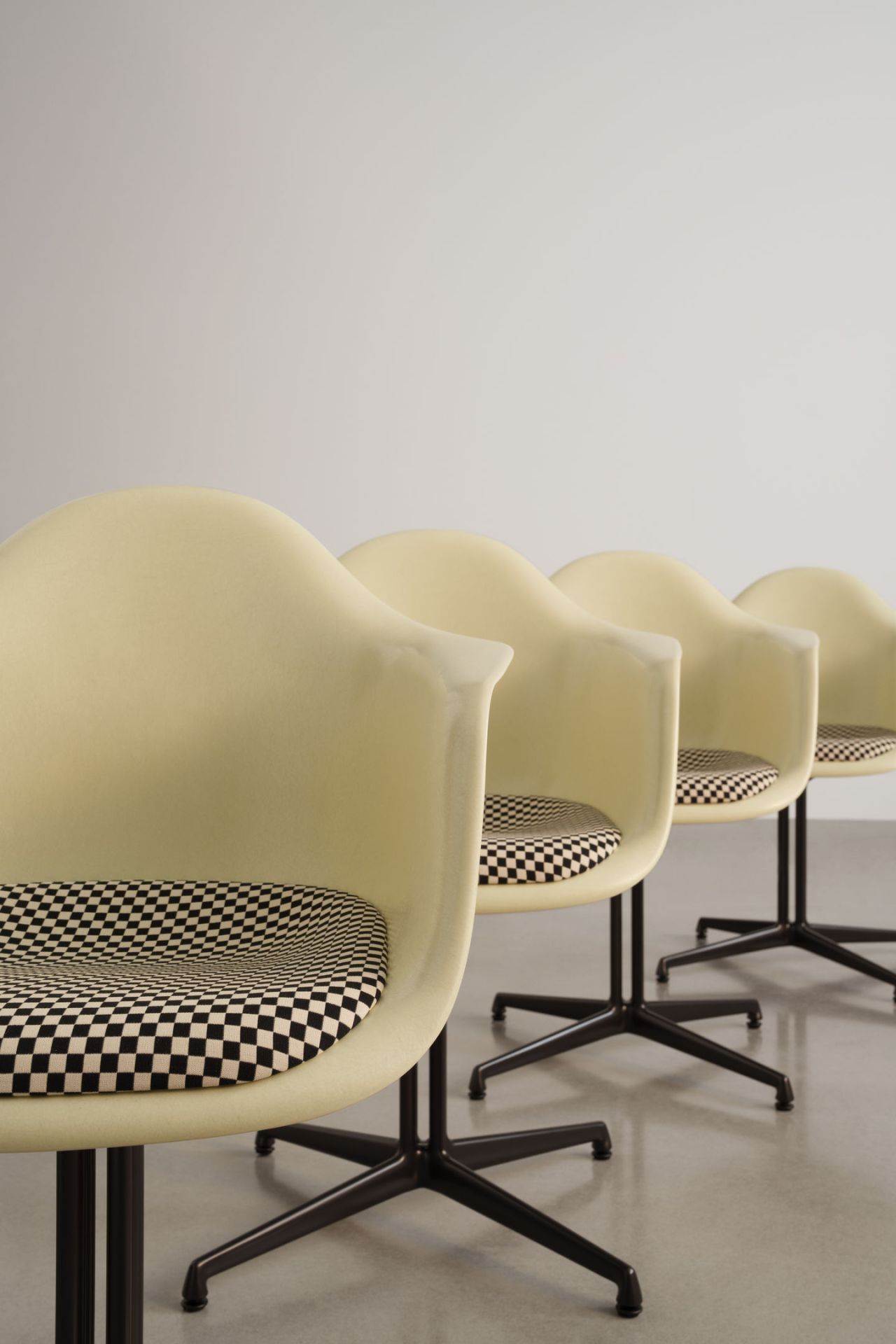 Reihe von Eames Plastic Arm Chairs DAL von Vitra mit Schachbrettmuster-Sitzpolster und schwarzem Untergestell.