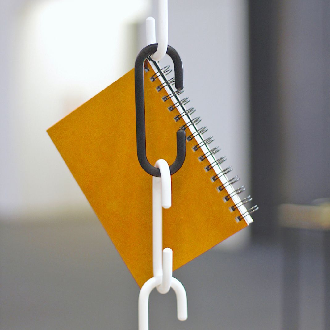 C + C Haken Roomsafari: Gelbes Notizbuch hängt an weißen und schwarzen Haken, flexibles Aufbewahrungssystem.
