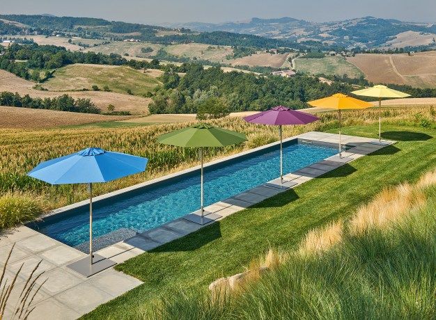 Weishäupl Klassiker Sonnenschirme in verschiedenen Farben am Pool mit Blick auf die Landschaft.