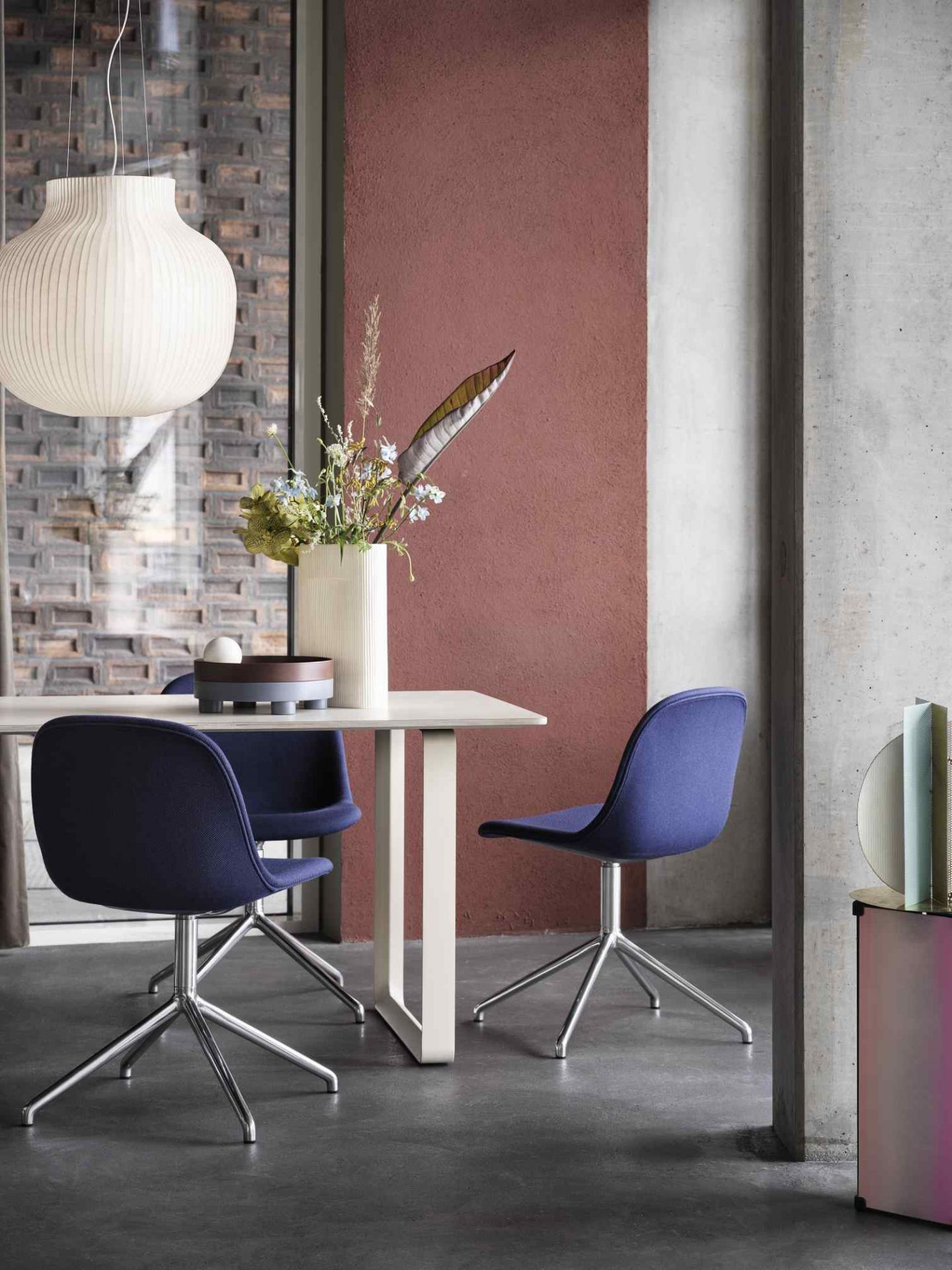 Muuto Strand Pendelleuchte über Esstisch mit blauen Stühlen in modernem Esszimmer.