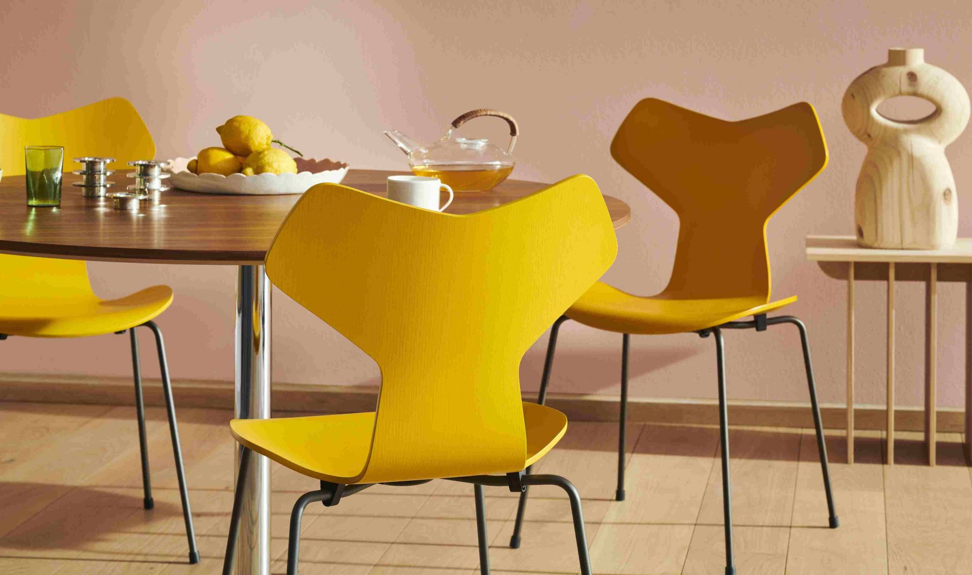 Gelbe Grand Prix Stühle von Fritz Hansen um einen Holztisch mit Teegeschirr und Zitronen.
