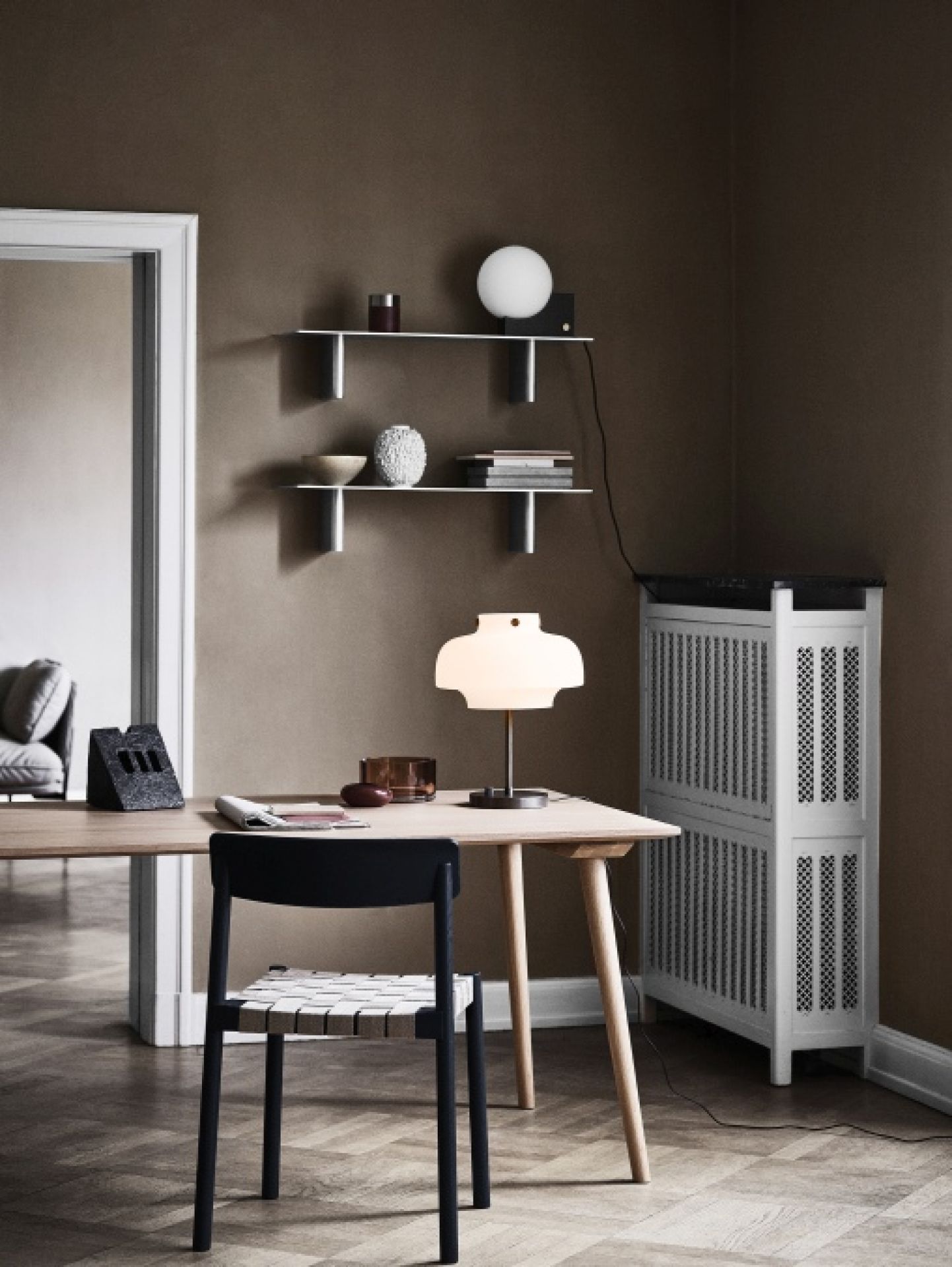 AndTradition In Between Tisch SK5 mit Lampe und Stuhl in einem stilvollen Wohnraum.