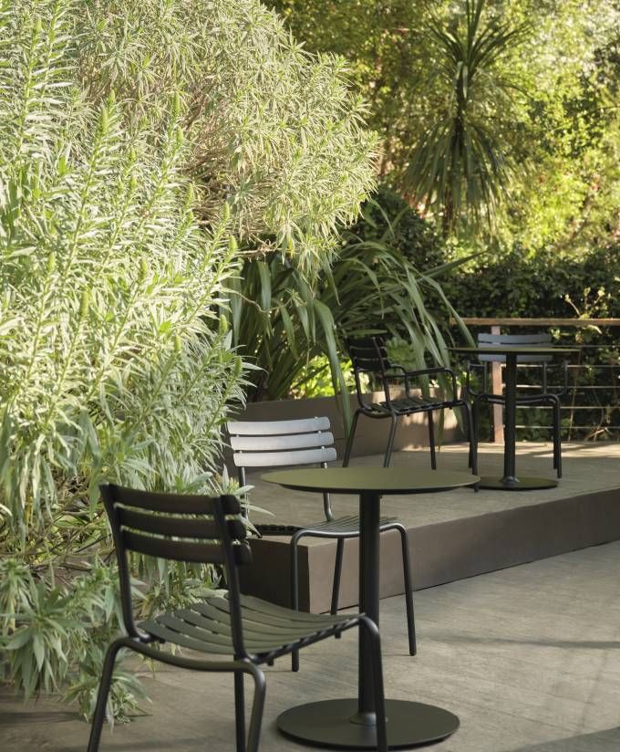 Alua Dining Chair von Houe, ein moderner Outdoor-Stuhl aus Metall in einer grünen Gartenszene.