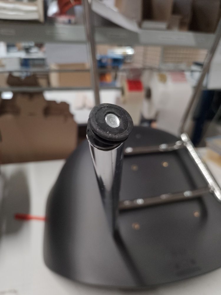 Detailaufnahme vom Fuß eines schwarzen About A Chair AAC26 Stuhls mit Chromgestell, Fokus auf den Bodengleiter.