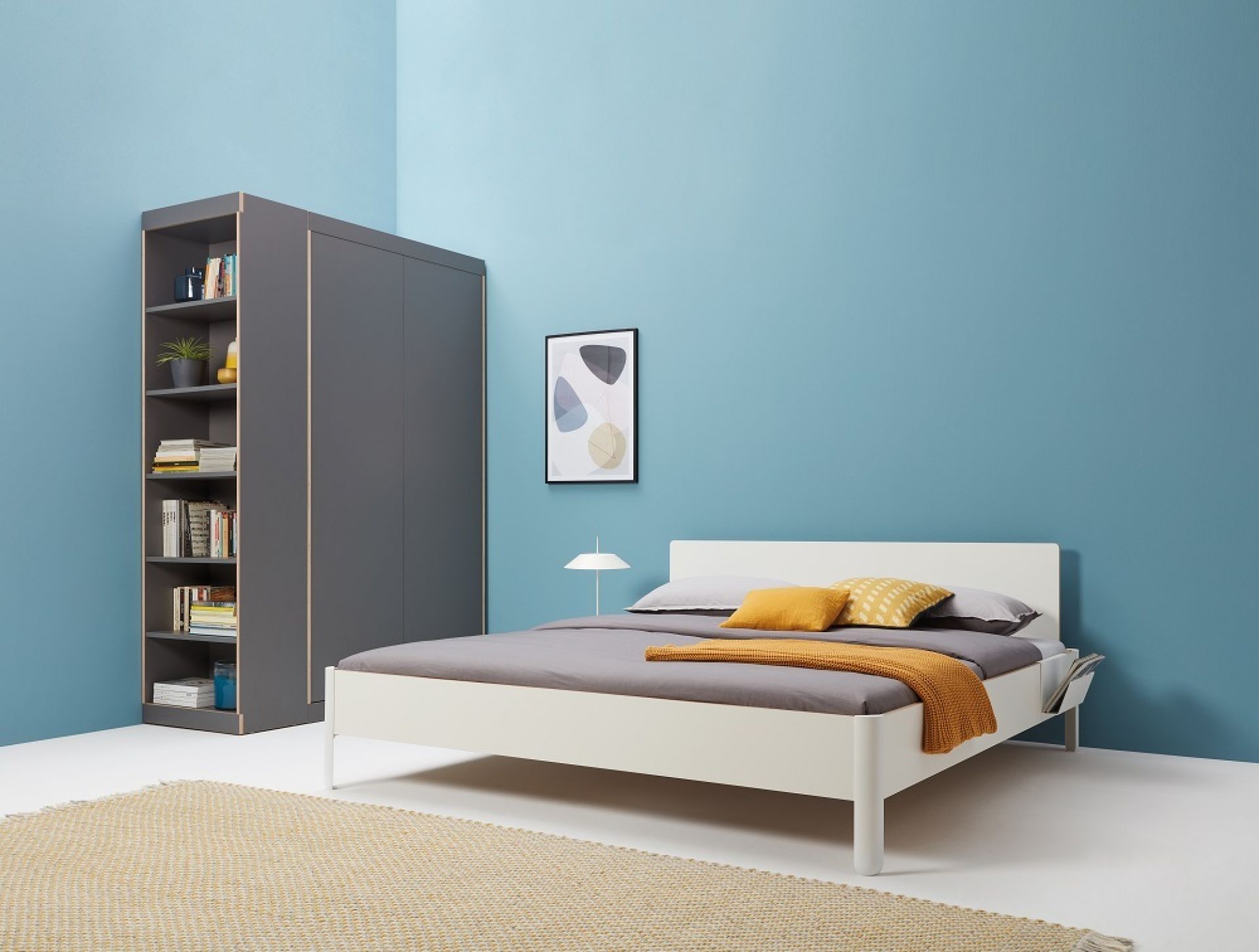 Nait Bett CPL Weiß von Müller Möbelwerkstätten mit grauem Schrank und Teppich auf blauem Hintergrund.