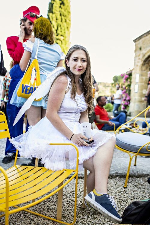 Eine Frau im weißen Kleid sitzt auf einem gelben Surprising Fermob Sessel im Freien.