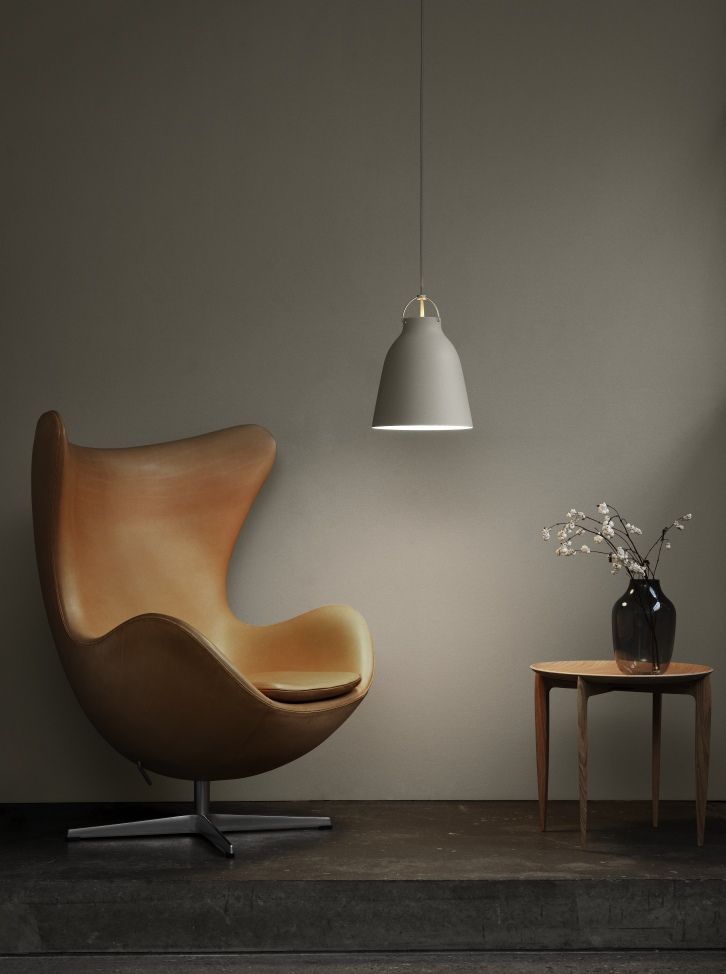 Moderne graue Caravaggio Pendelleuchte von Fritz Hansen über Sessel und Beistelltisch im Wohnzimmer.