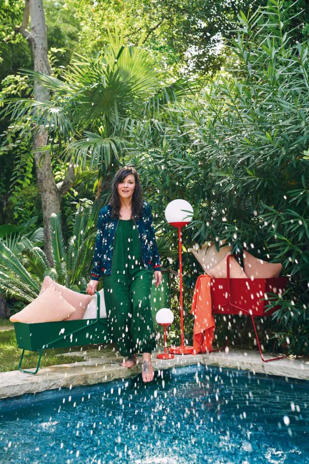 Frau mit Fermob Basket Blumenkasten in Grün und Rot am Pool. Gartenmöbel und Accessoires.