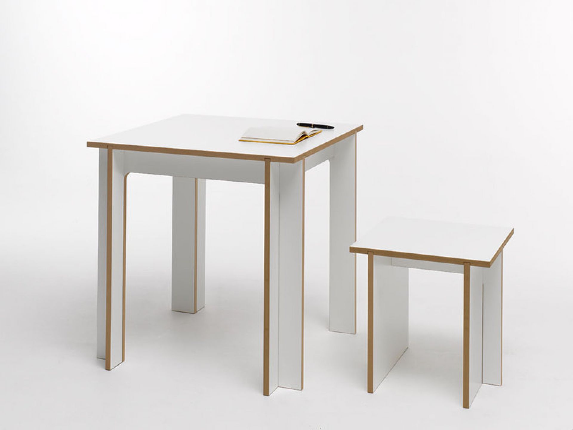 Tojo Tischgruppe mit Hocker, quadratischer Esstisch aus Holz, weiß lackiert mit Notizbuch und Stift.