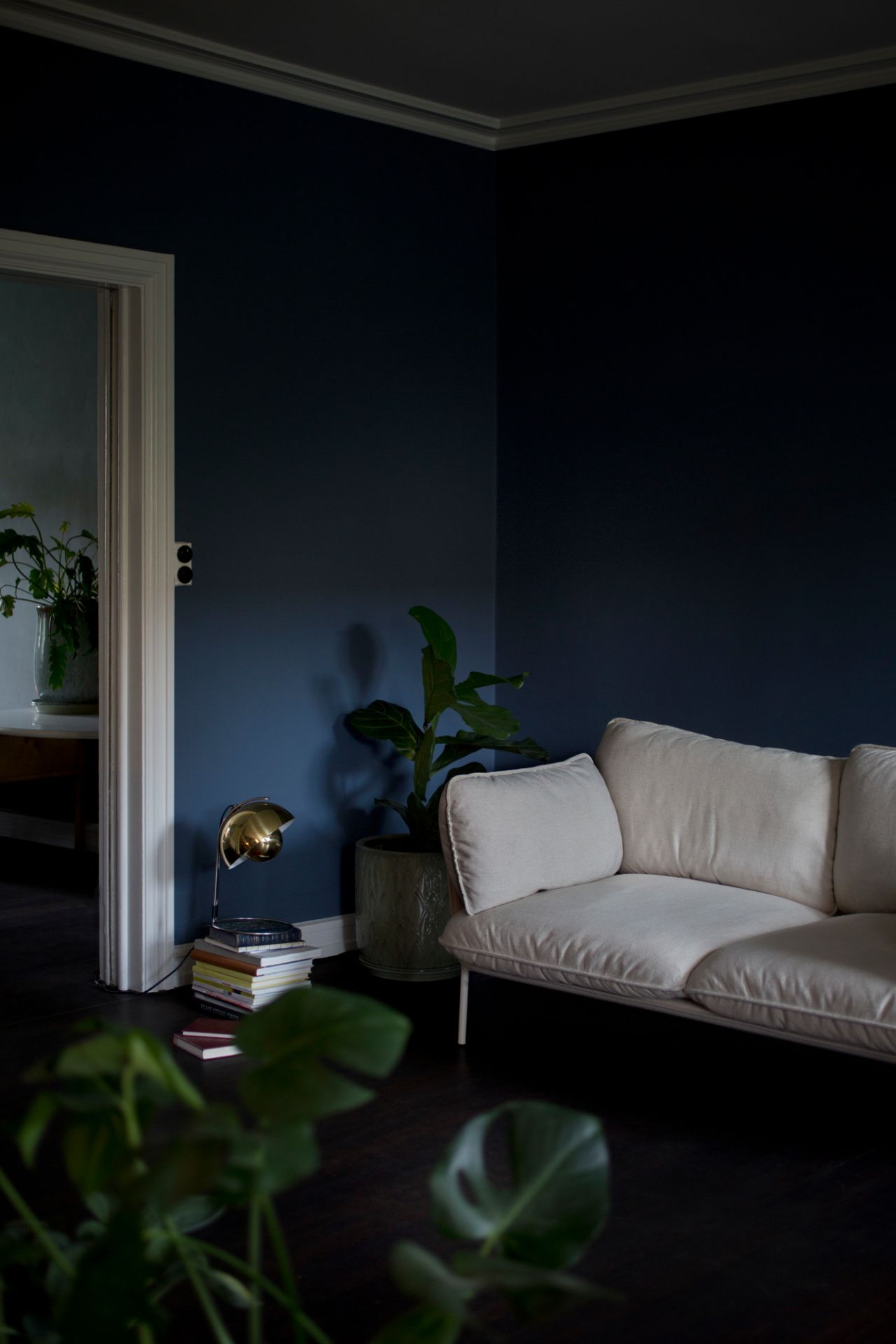 Beige Cloud Sofa von AndTradition in dunklem Wohnzimmer mit Pflanze und Lampe.
