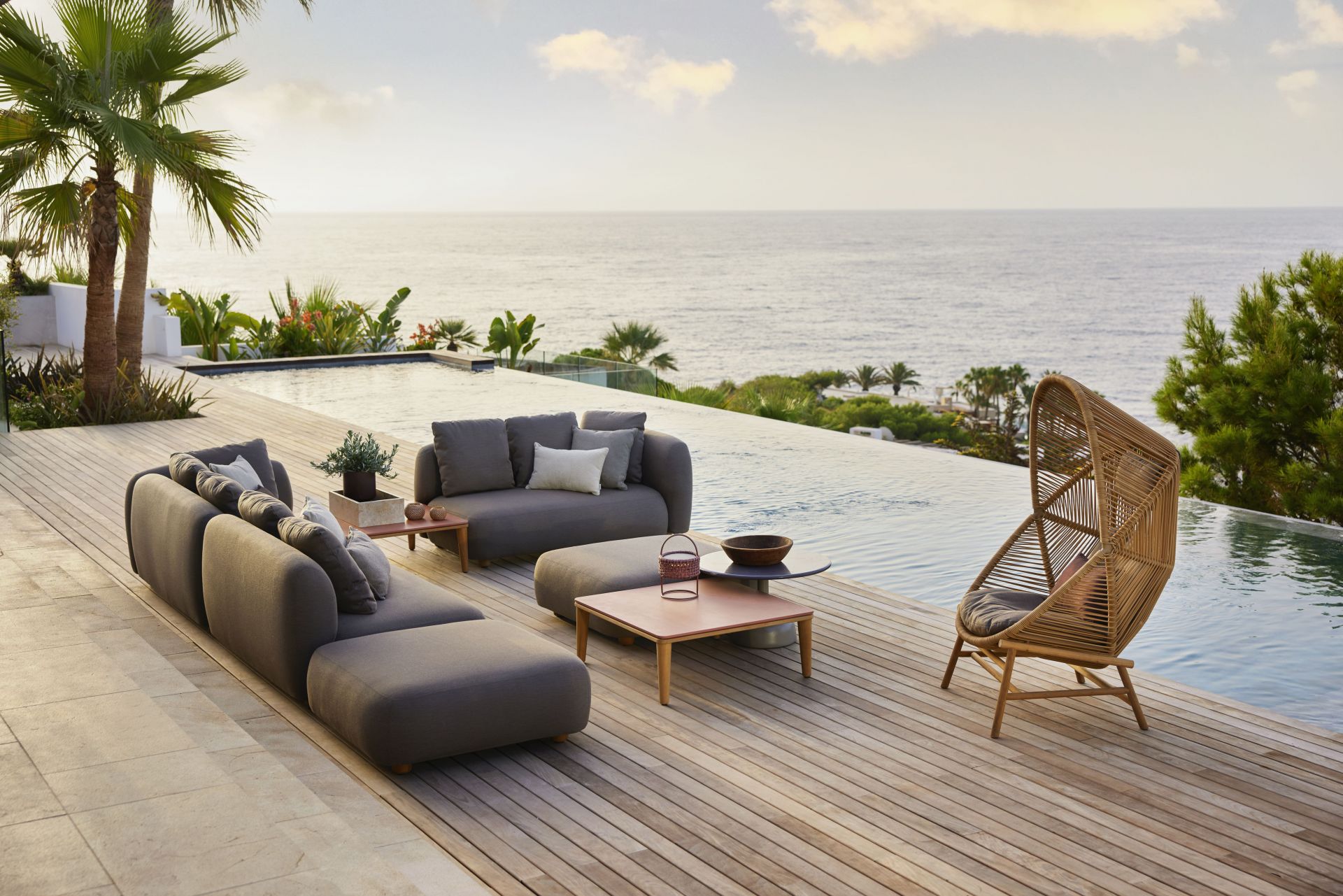 Cane-Line Capture Outdoor Couchtisch auf Holzterrasse mit Meerblick, Lounge Möbel und Rattansessel.
