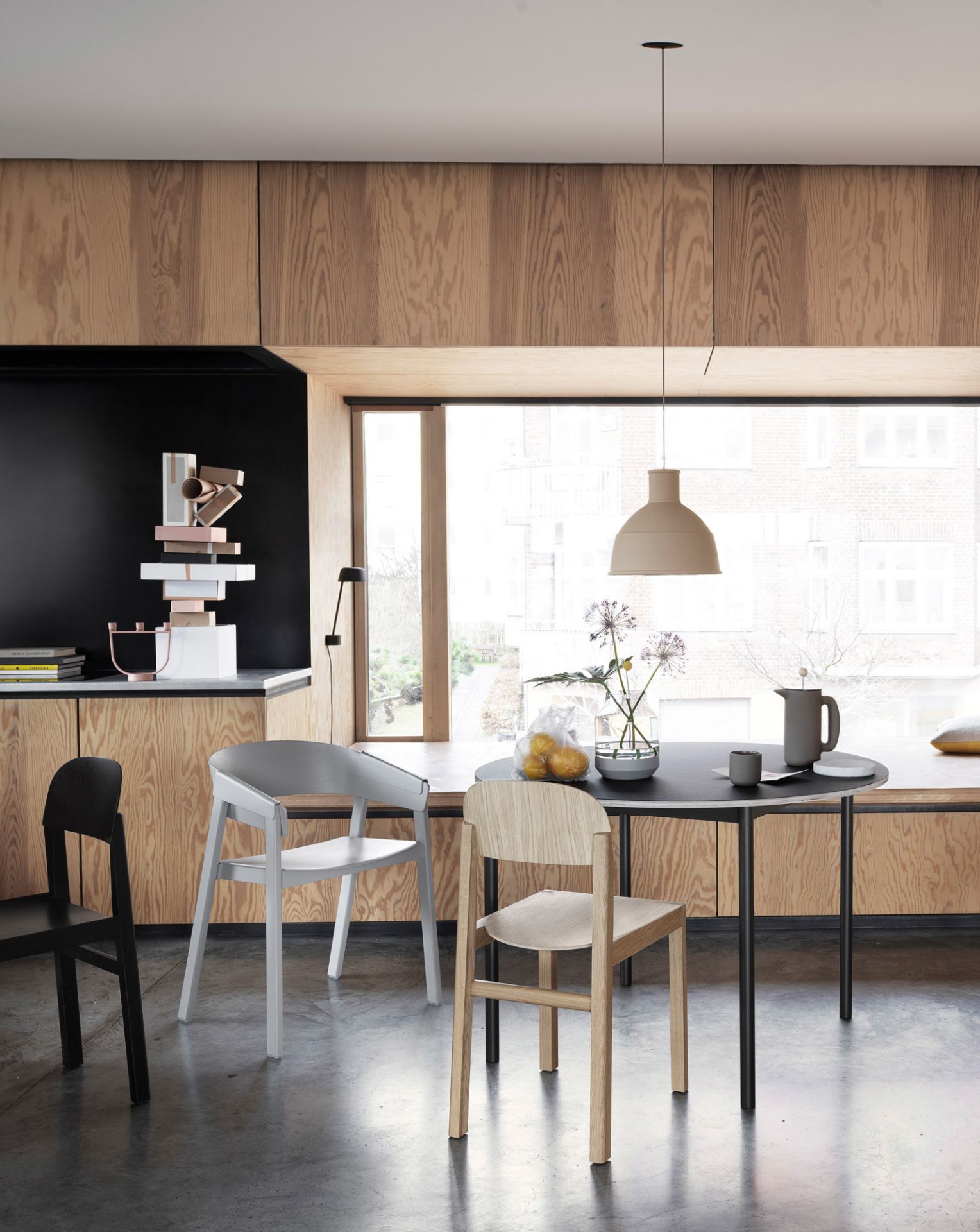Muuto Base Table runder Esstisch mit schwarzer Tischplatte und drei Stühlen in modernem Interieur.