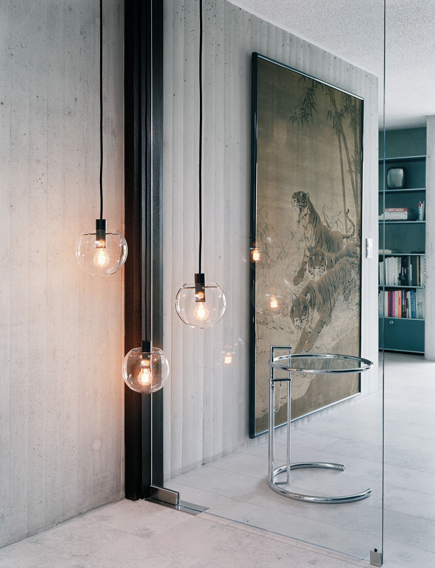 ClassiCon Adjustable Table E1027 Beistelltisch im modernen Interieur mit Betonwand, Hängelampen und Tiger-Wandbild.