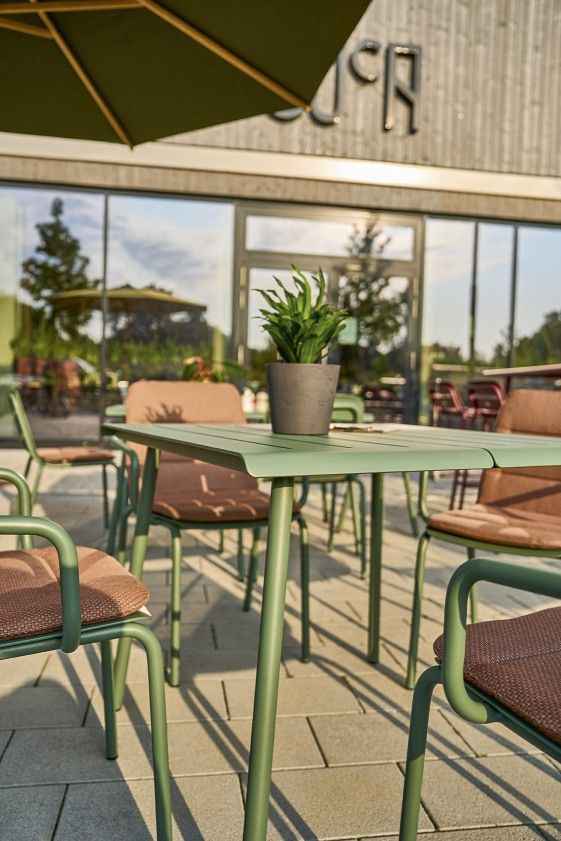Weishäupl Vapio Tisch Outdoor mit grüner Tischplatte und Stühlen auf einer Terrasse.