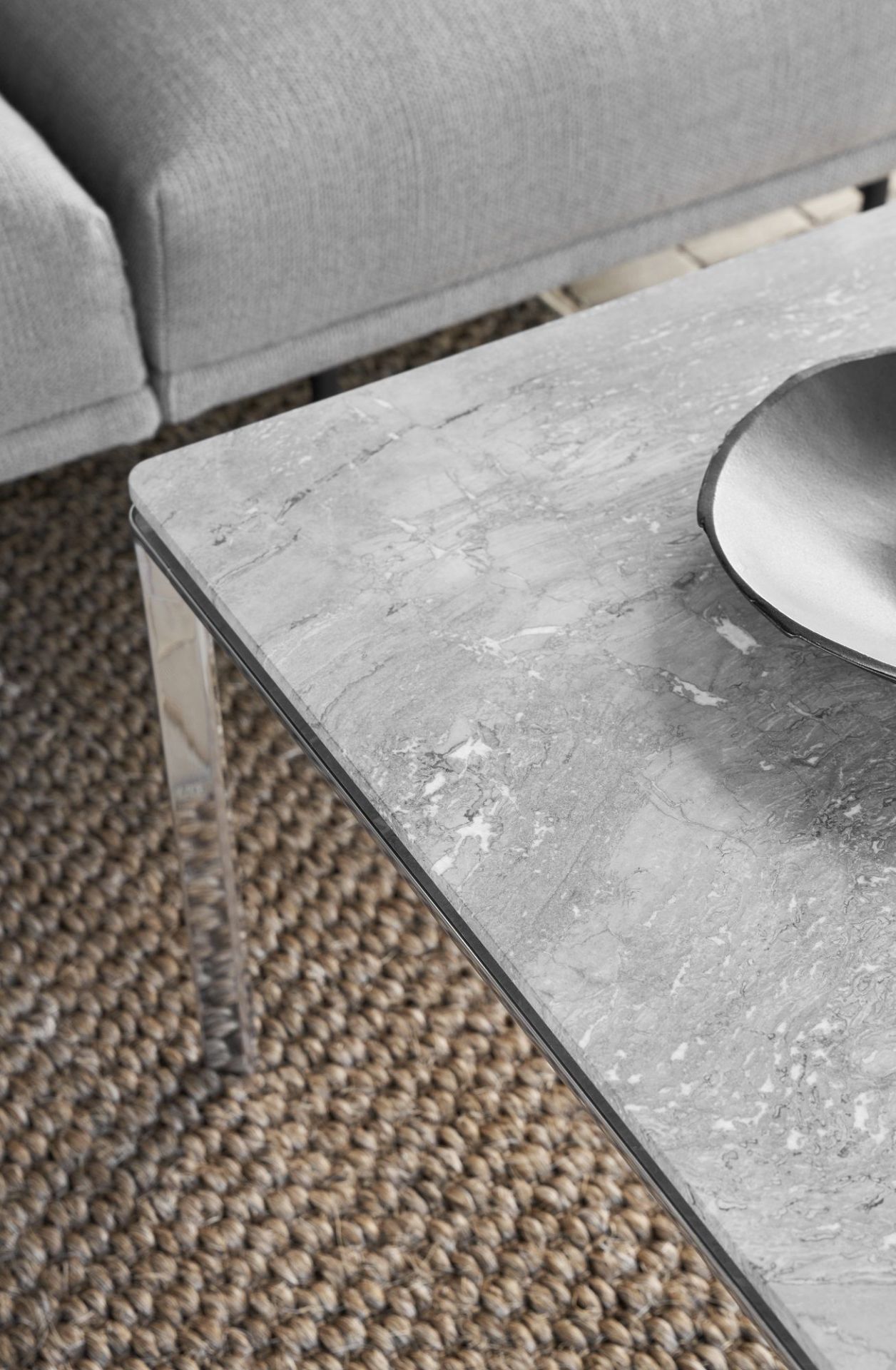 Detailaufnahme vom Vipp Couchtisch mit grauer Marmorplatte und silbernem Rahmen auf einem Teppich.