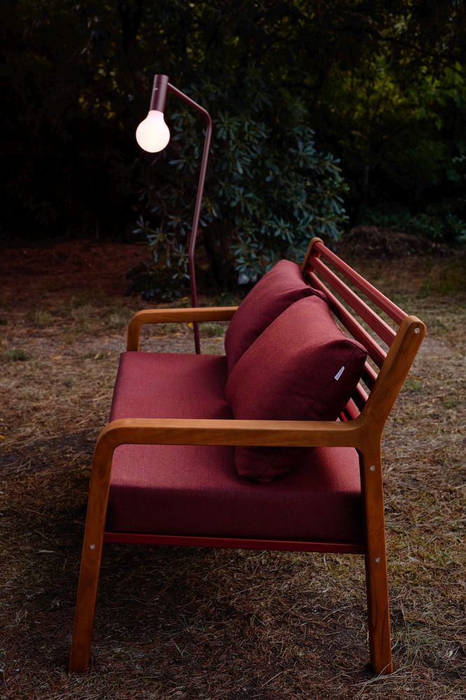 Nahaufnahme des roten Somerset 2-Sitzer Outdoor Sofas von Fermob mit Holzelementen und passenden Kissen.