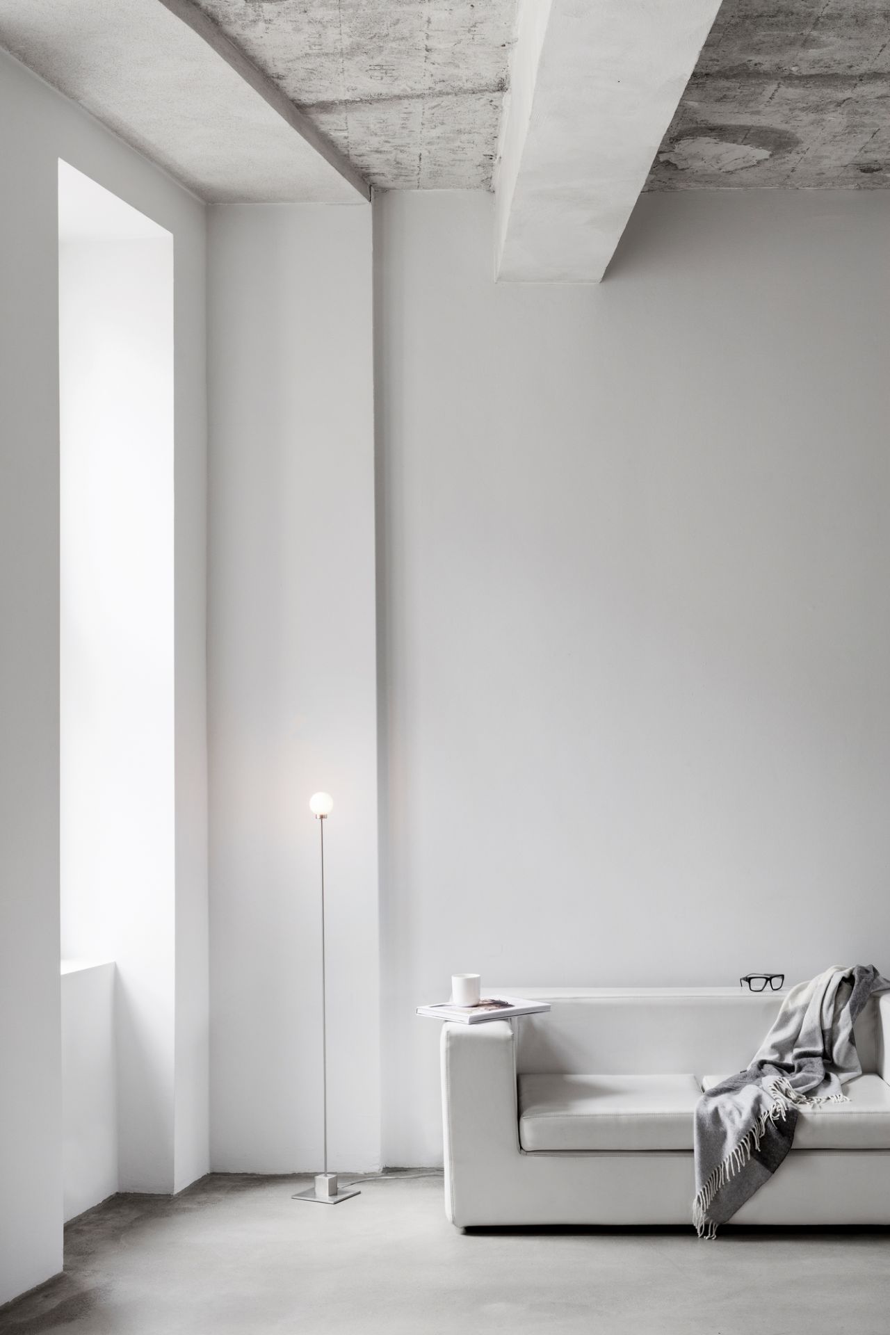 Minimalistische, weiße Inneneinrichtung mit Snowball LED Stehleuchte von Northern, Sofa, Decke und Betonboden.
