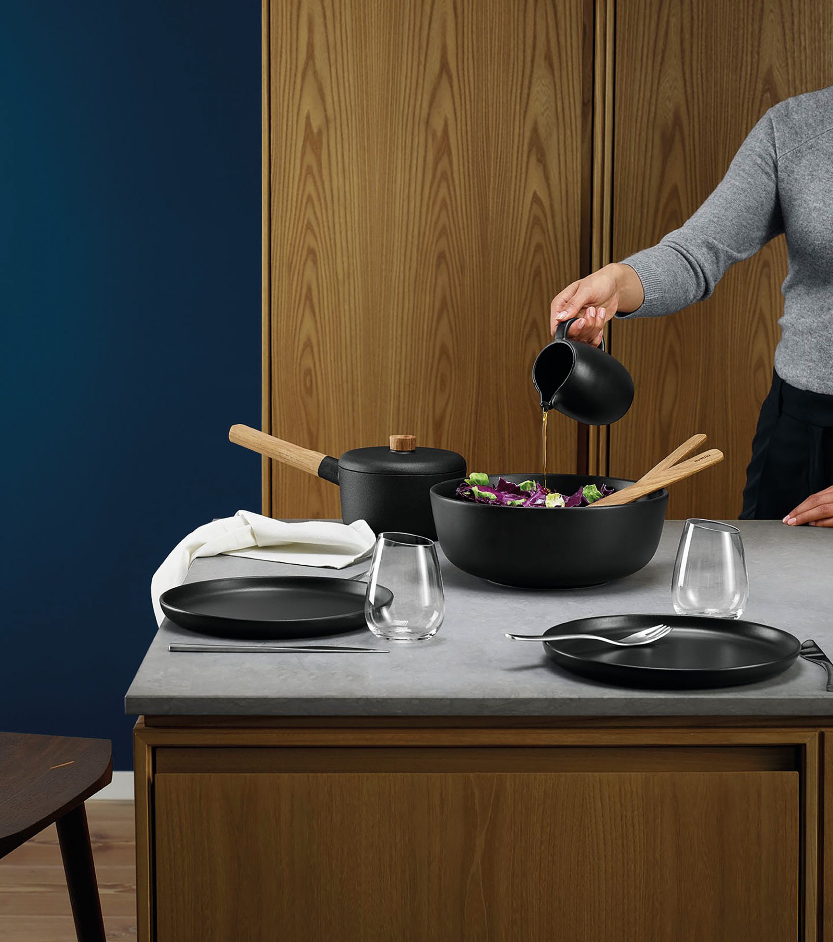 Nordic Kitchen Kanne von Eva Solo beim Ausgießen von Dressing über einen Salat.
