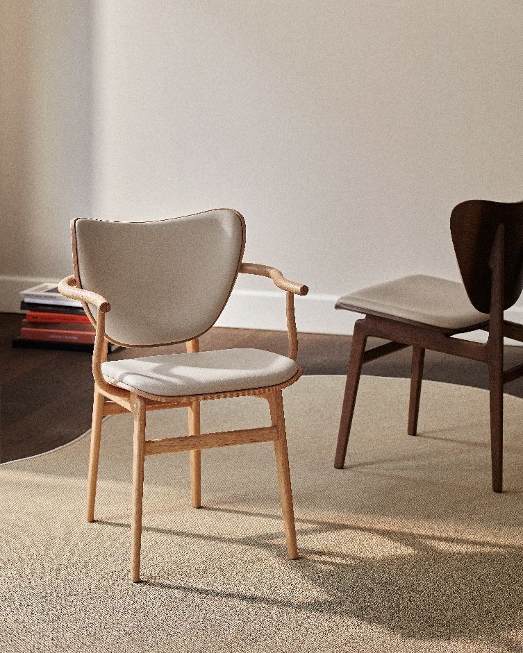 NORR11 Elephant Dining Armchair mit Armlehnen, helles Holzgestell und beigem Sitzpolster im Interieur.