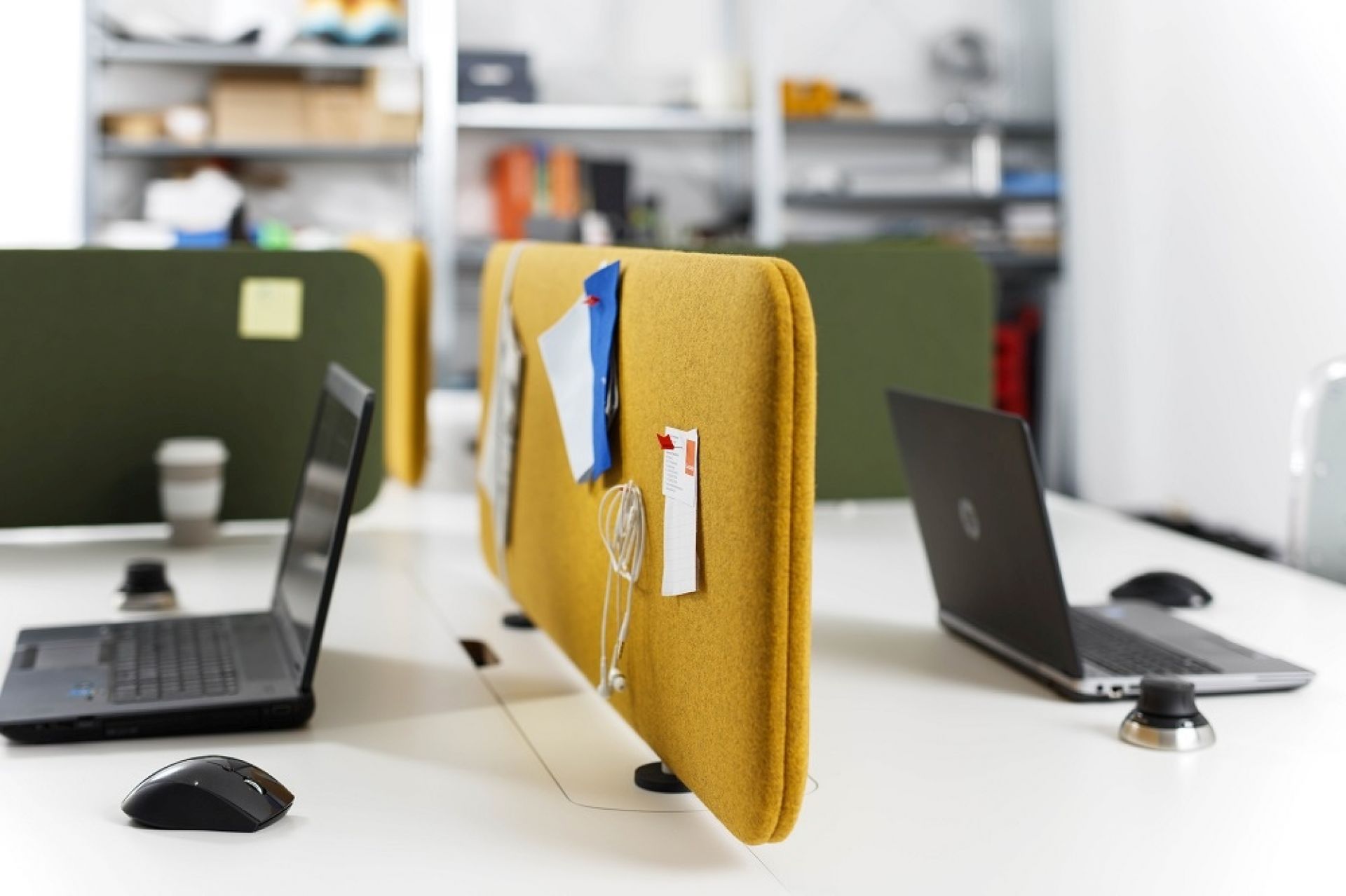 Gelbes Cascando Pillow Desk Akustikelement auf einem Schreibtisch mit Laptop und Büroartikeln. Schallschutz für Büro.