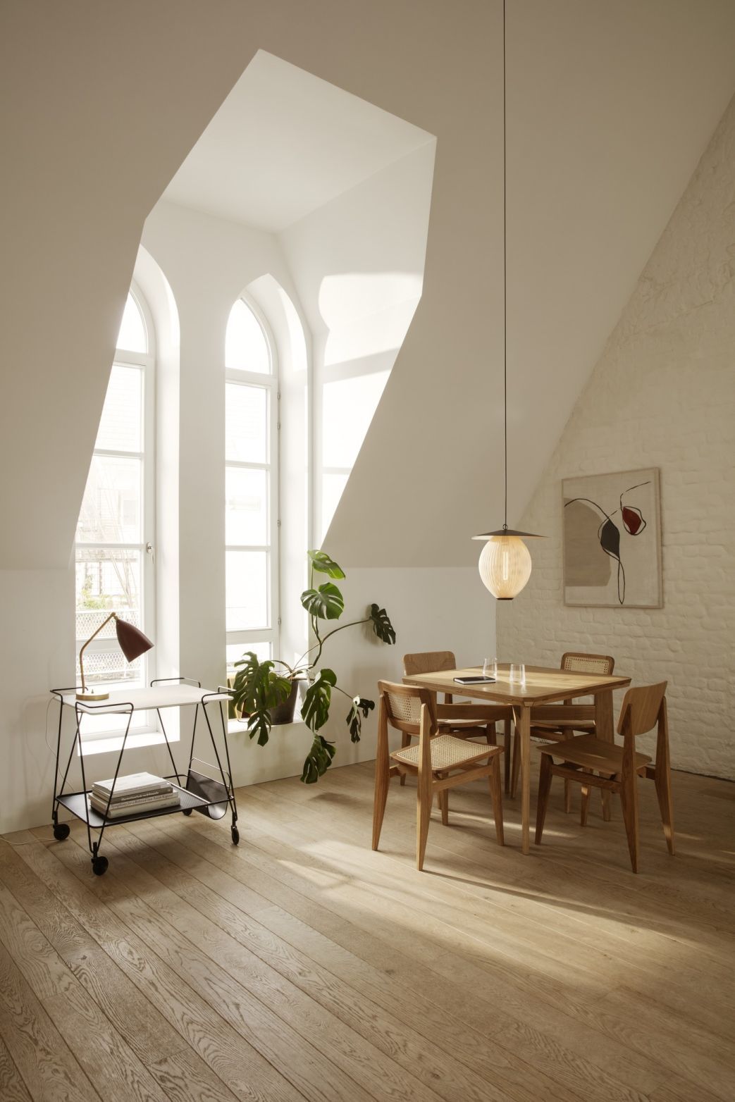 Heller Raum mit Gubi B-Table Esstisch ausziehbar aus Holz und passenden Stühlen unter Pendelleuchte.