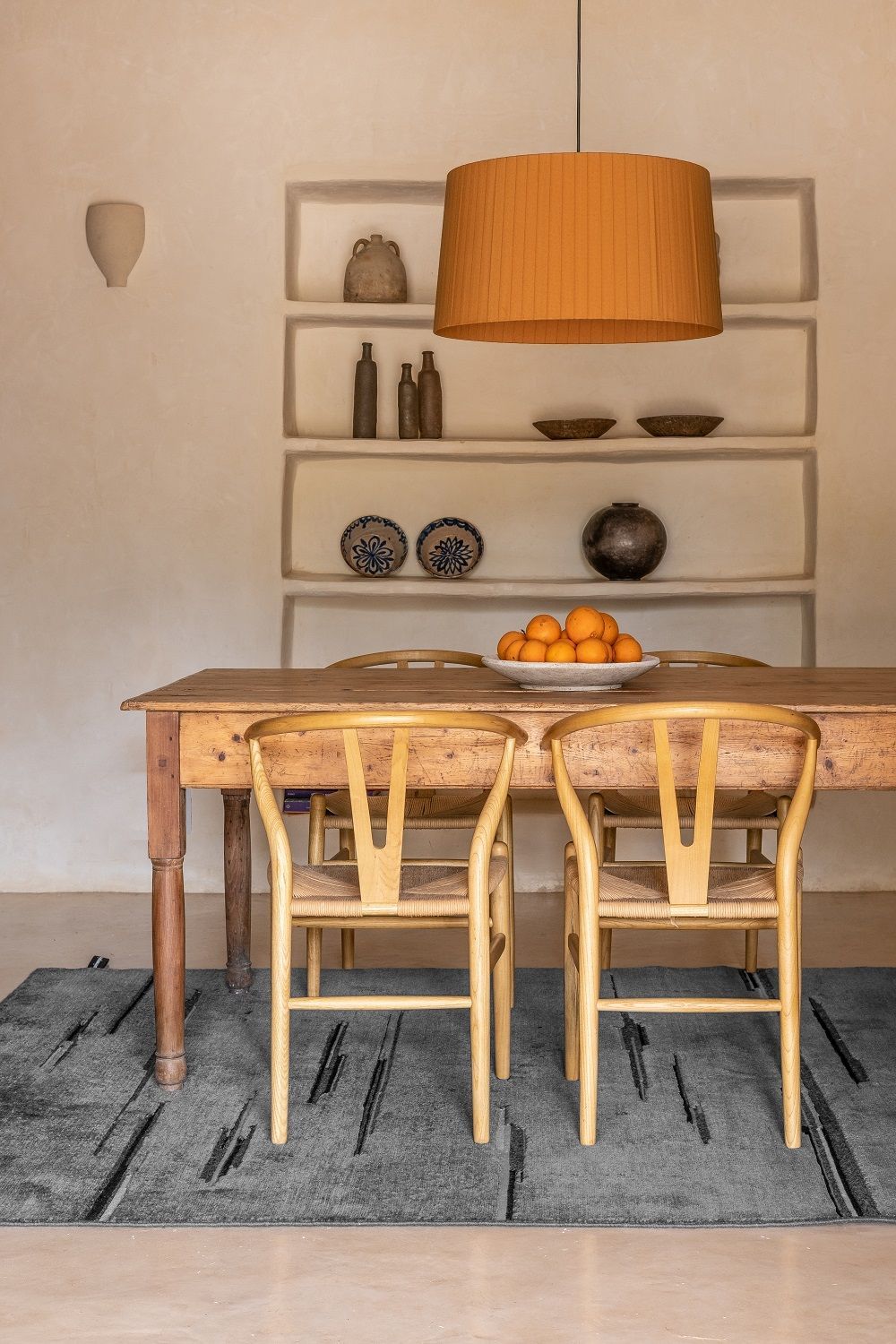 Colorado Teppich von Nanimarquina in grau unter einem Holzesstisch mit Stühlen und Obstschale.