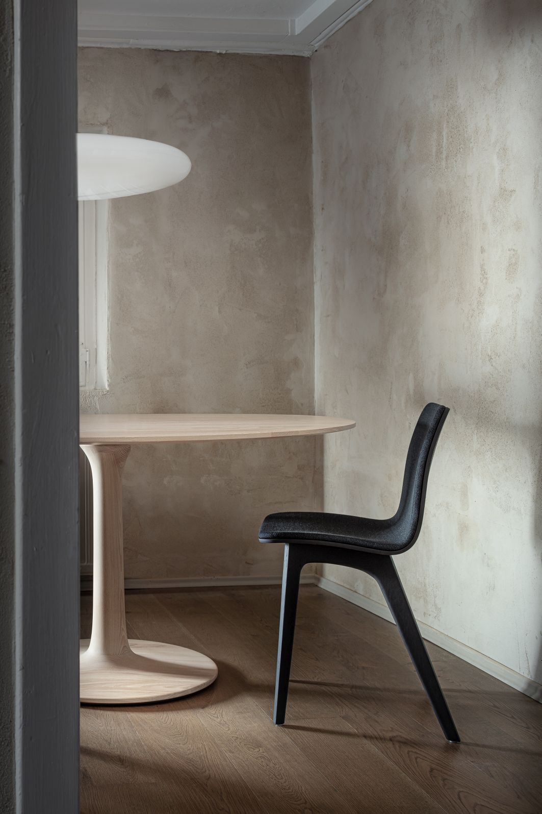 Nahaufnahme des Turntable Esstischs Zeitraum aus hellem Holz mit schwarzem Stuhl in minimalistischem Interieur.