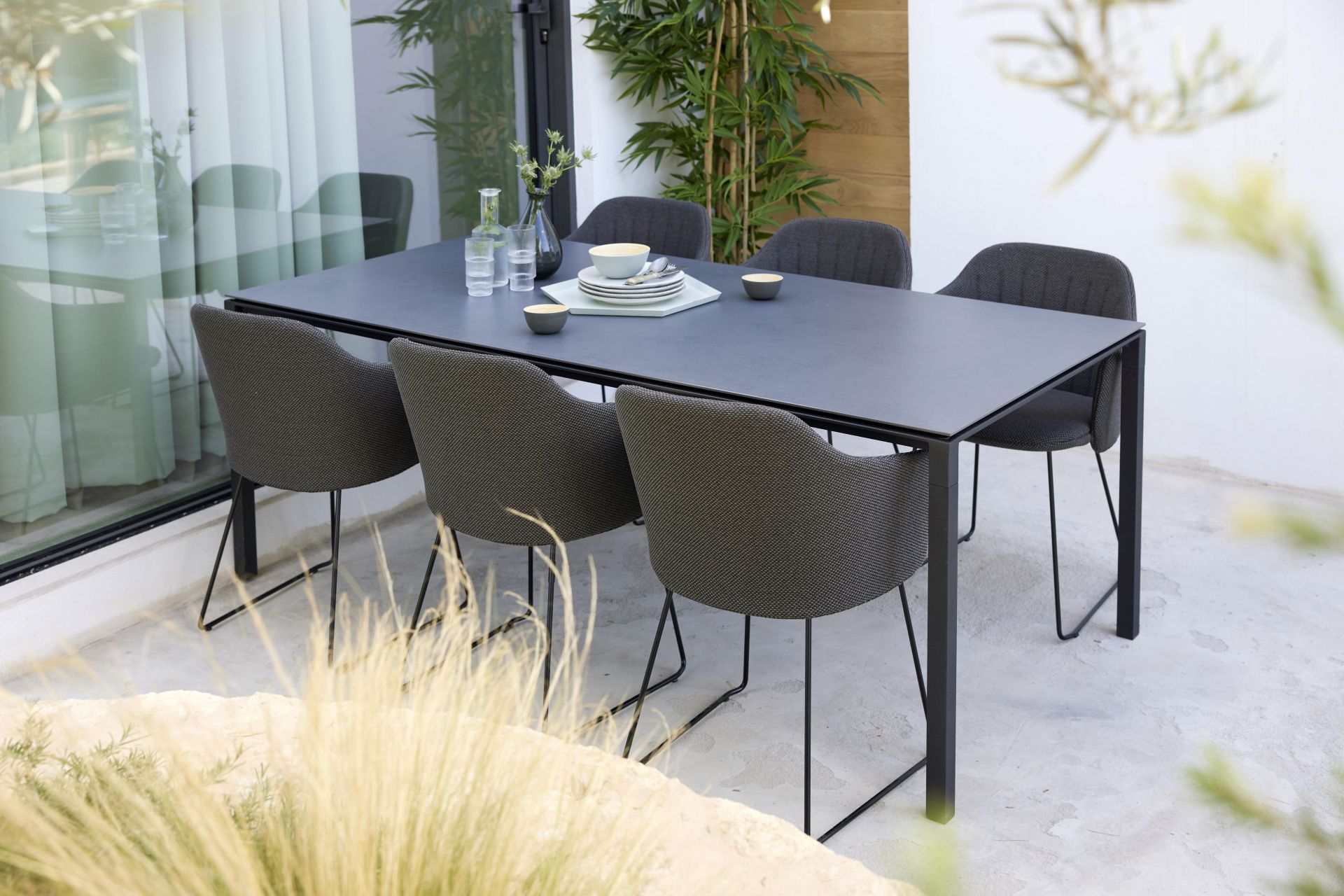 Choice Outdoor Stuhl von Cane-Line mit Stahlgestell und grauer Textilbespannung am Esstisch.